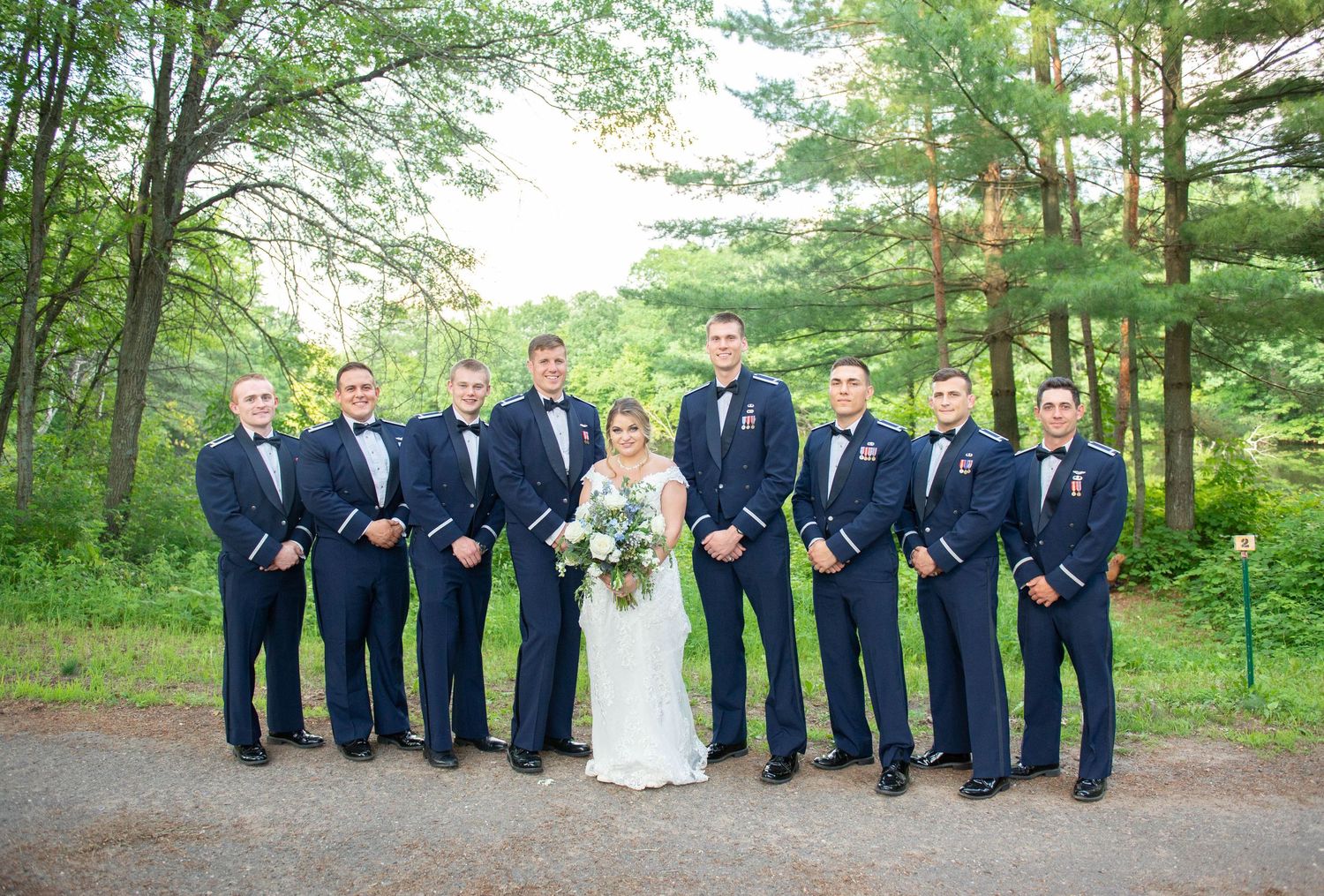 Formal wedding party lineup on a wooded path with groomsmen in navy suits. Zimmerman MN Weddings