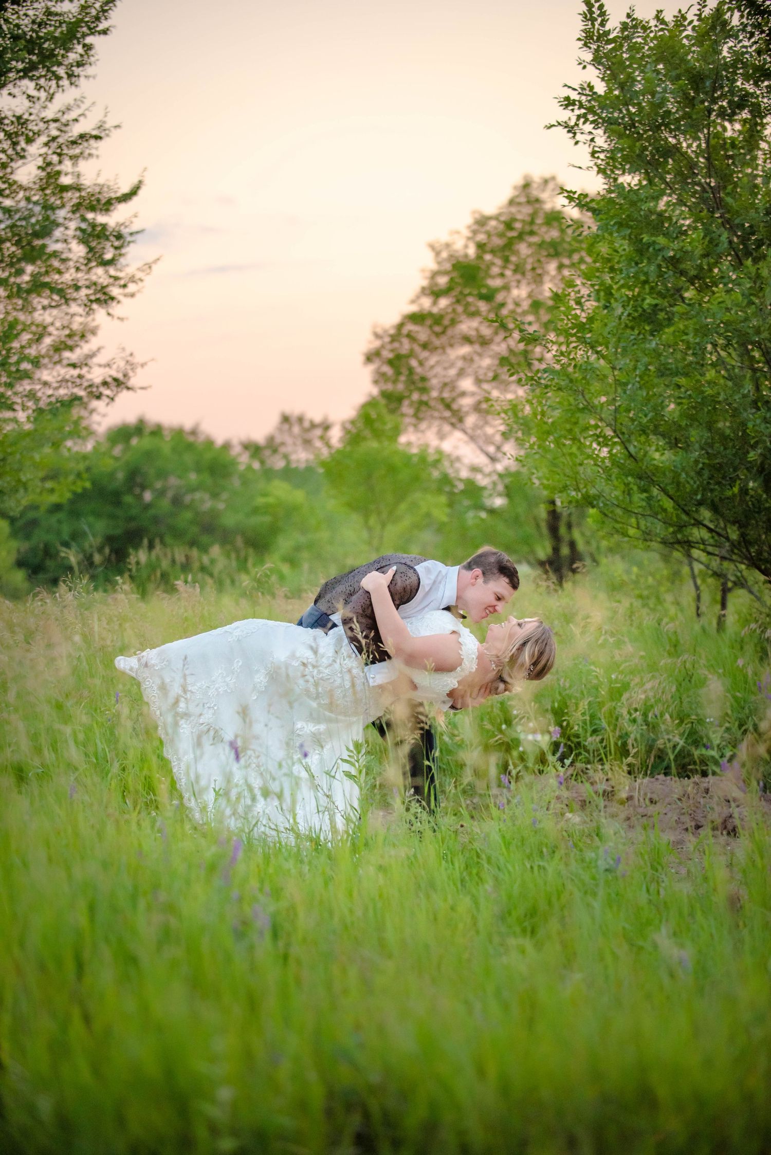 Romantic dip pose with couple in grassy field during sunset wedding photoshoot. Zimmerman MN Weddings