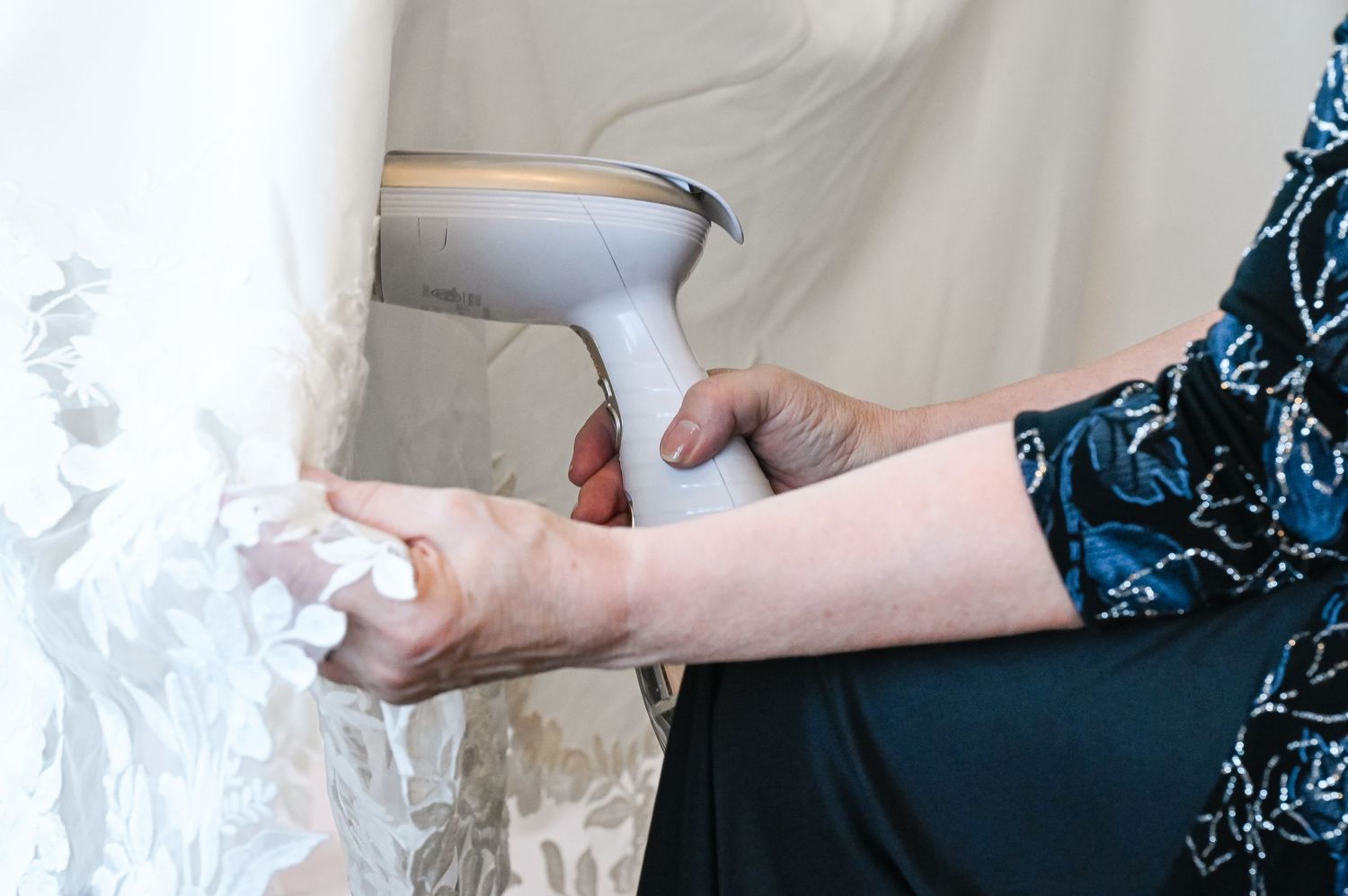 Hands using a roller to apply white paint on a wall during home renovation.