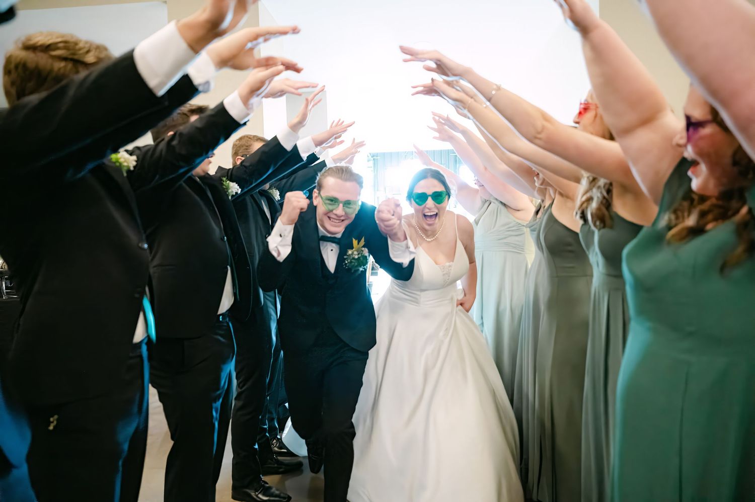 Wedding guests performing a synchronized dance move with their arms raised in celebration.