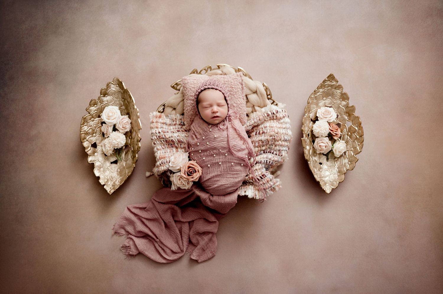 Sleeping newborn posed in vintage-style setting with floral arrangements.