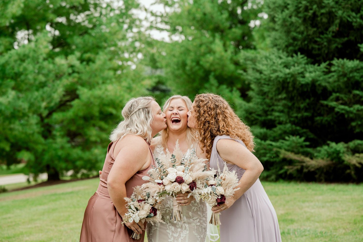 Bridal party shares a joyful laughing moment on the lawn with floral bouquets.