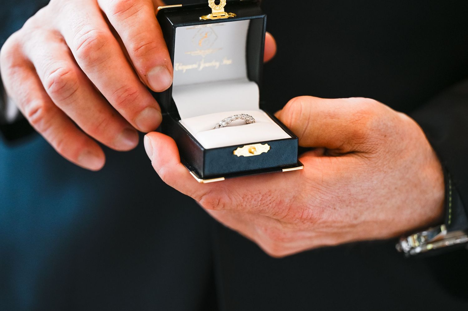 Close-up of hands holding wedding ring box during ceremony proposal moment.