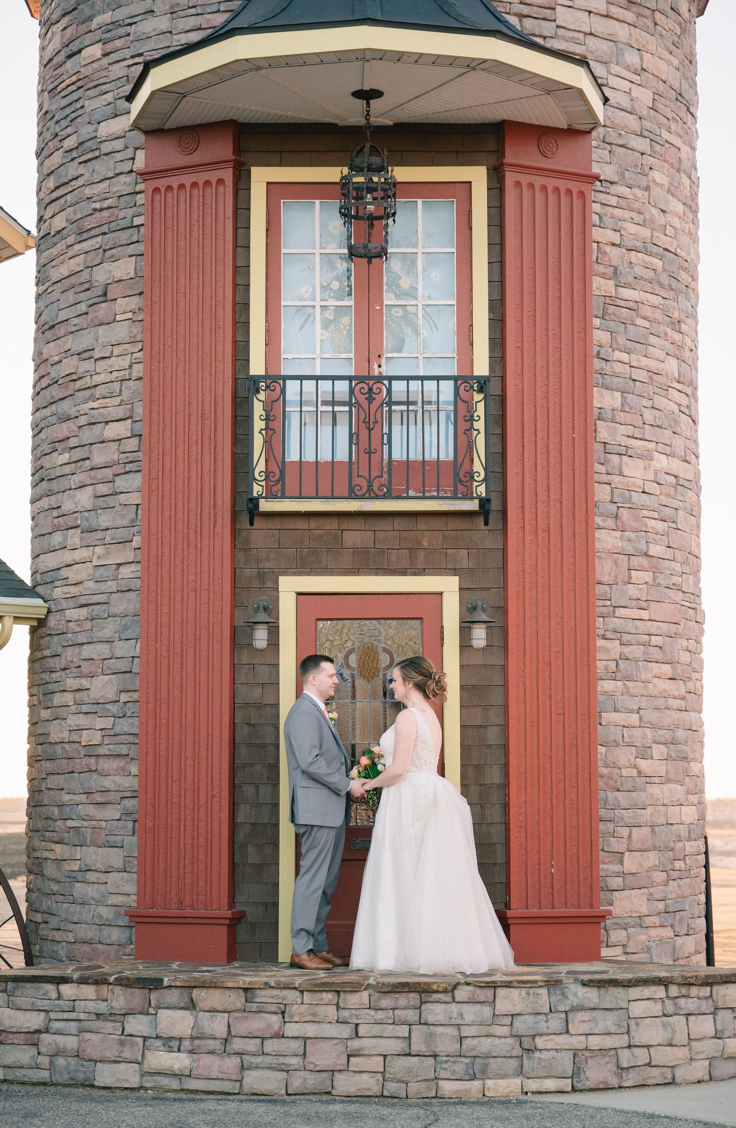 Bride and groom standing before charming brick tower venue entrance.