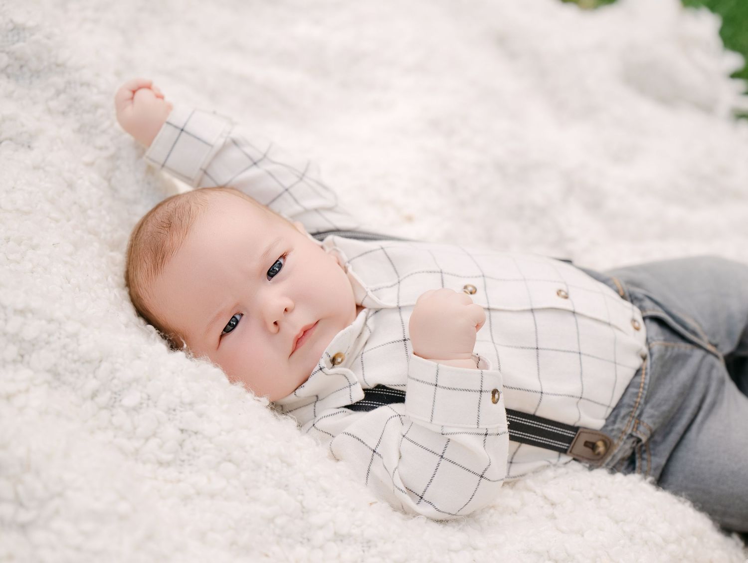 Baby in white checkered outfit with suspenders lying on soft white blanket.. Minnesota milestone photographer