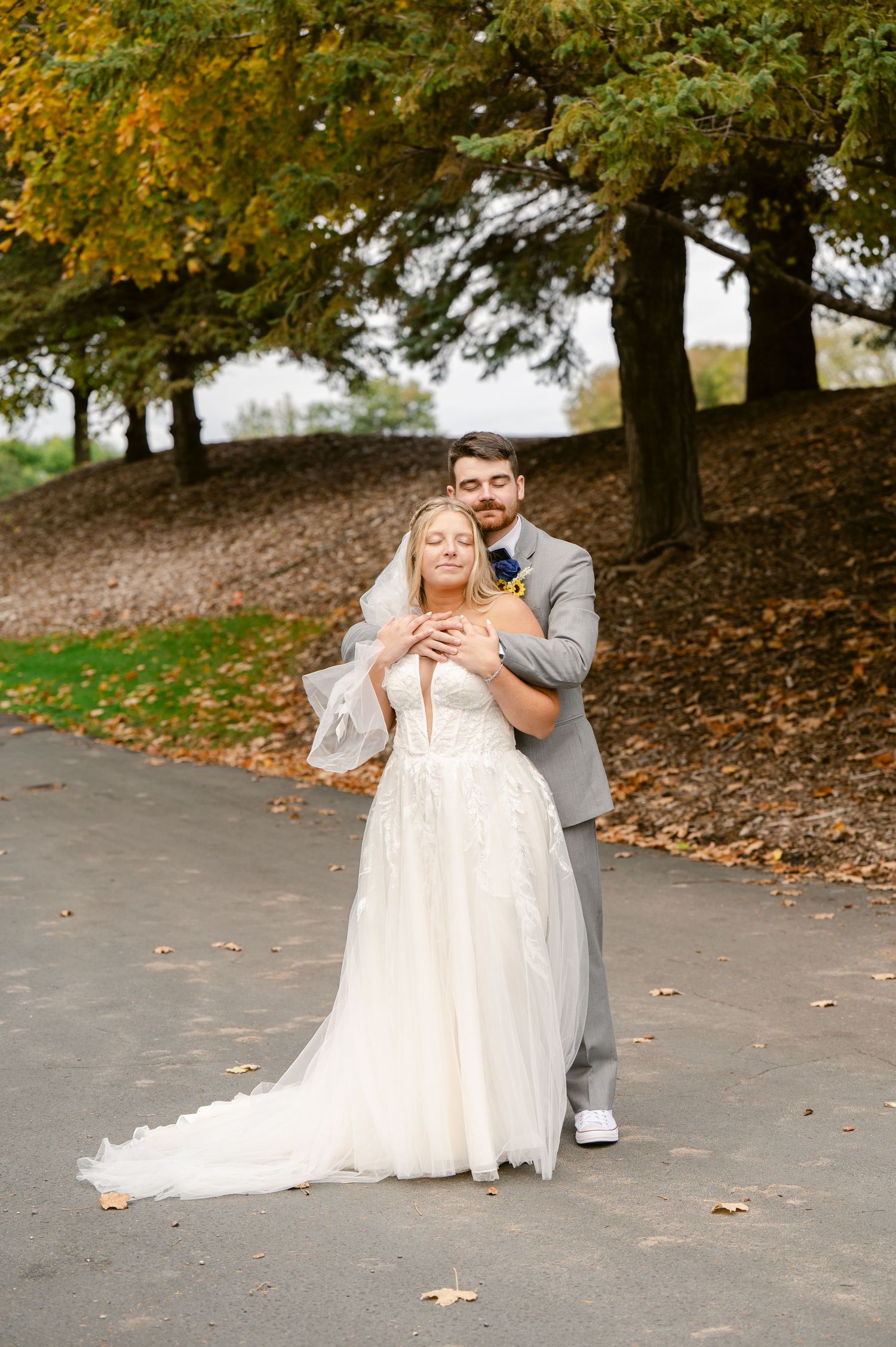 Central MN Wedding Photos | Groom embraces bride from behind in elegant fall outdoor wedding portrait.