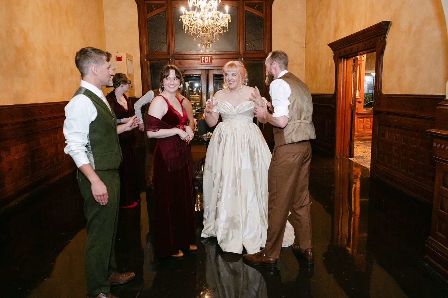 Central MN Wedding Photos | Bride in ivory ball gown socializes with wedding guests in burgundy and green attire.