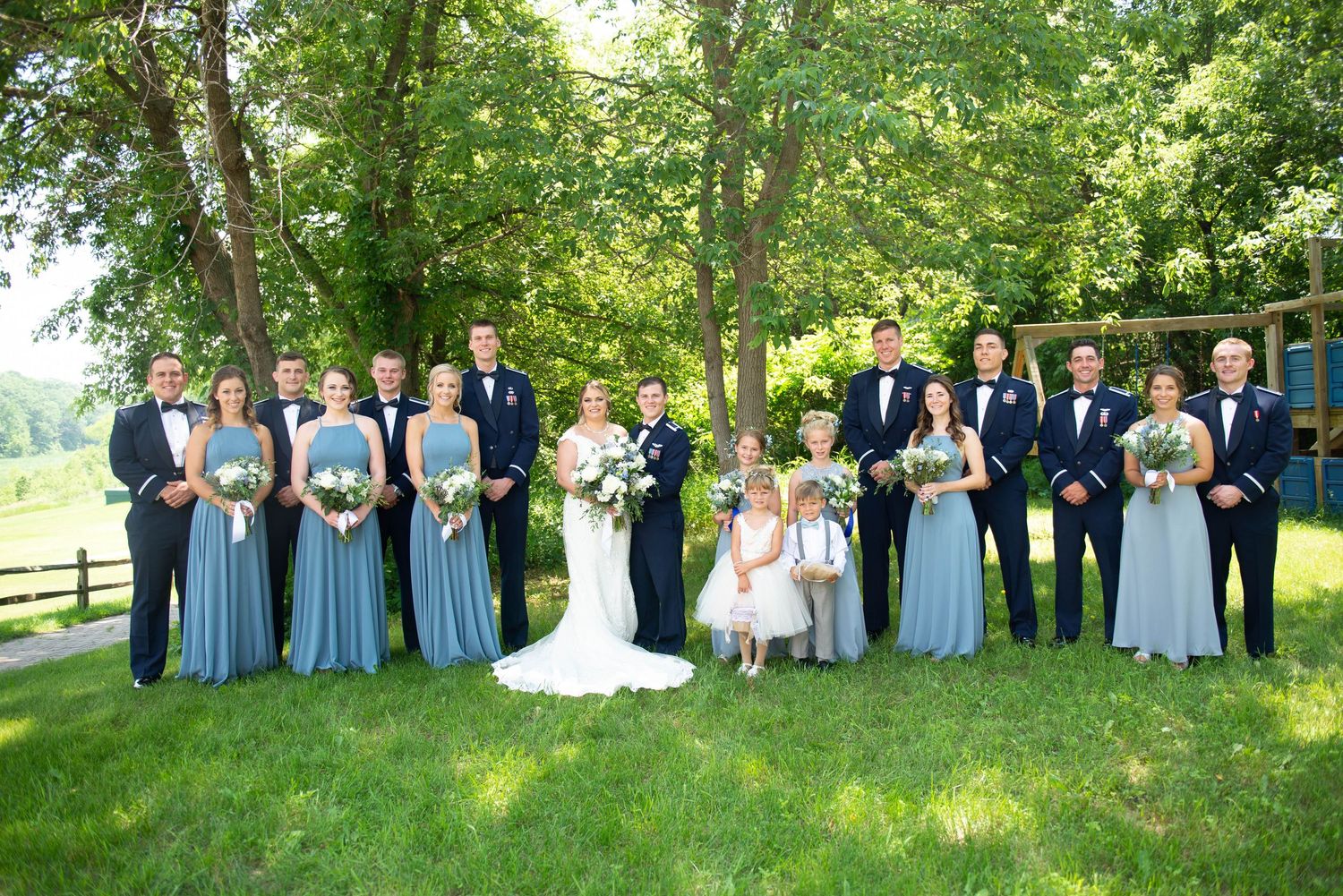 Large wedding party posed on grassy hillside wearing navy and light blue attire. Zimmerman MN Weddings