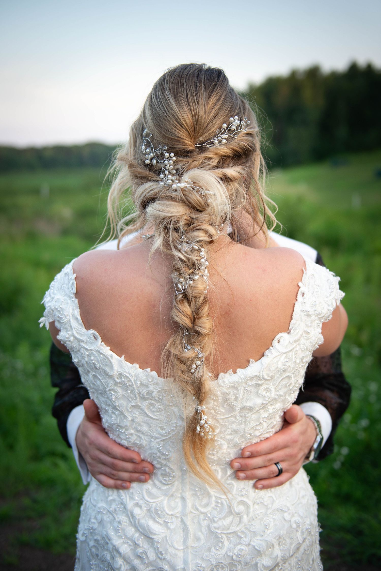Back view of bride showing intricate lace dress and braided hairstyle with floral accents.  Zimmerman MN Weddings