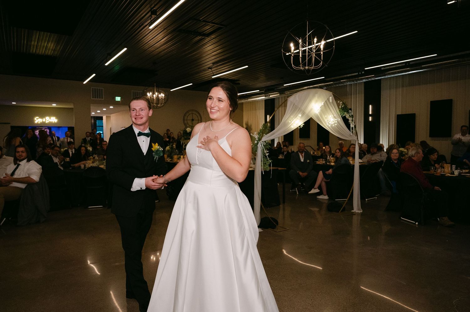 Wedding reception dance floor with guests celebrating under indoor lighting.