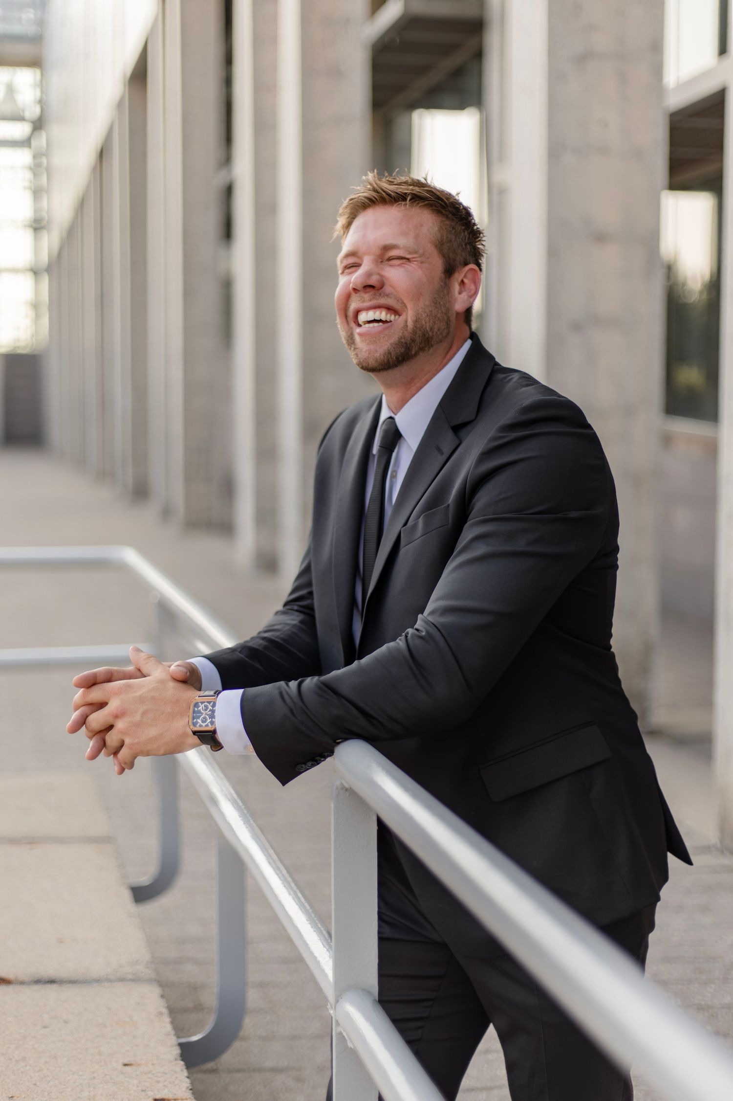 Person in suit leaning on metal railing displaying joyful expressions.