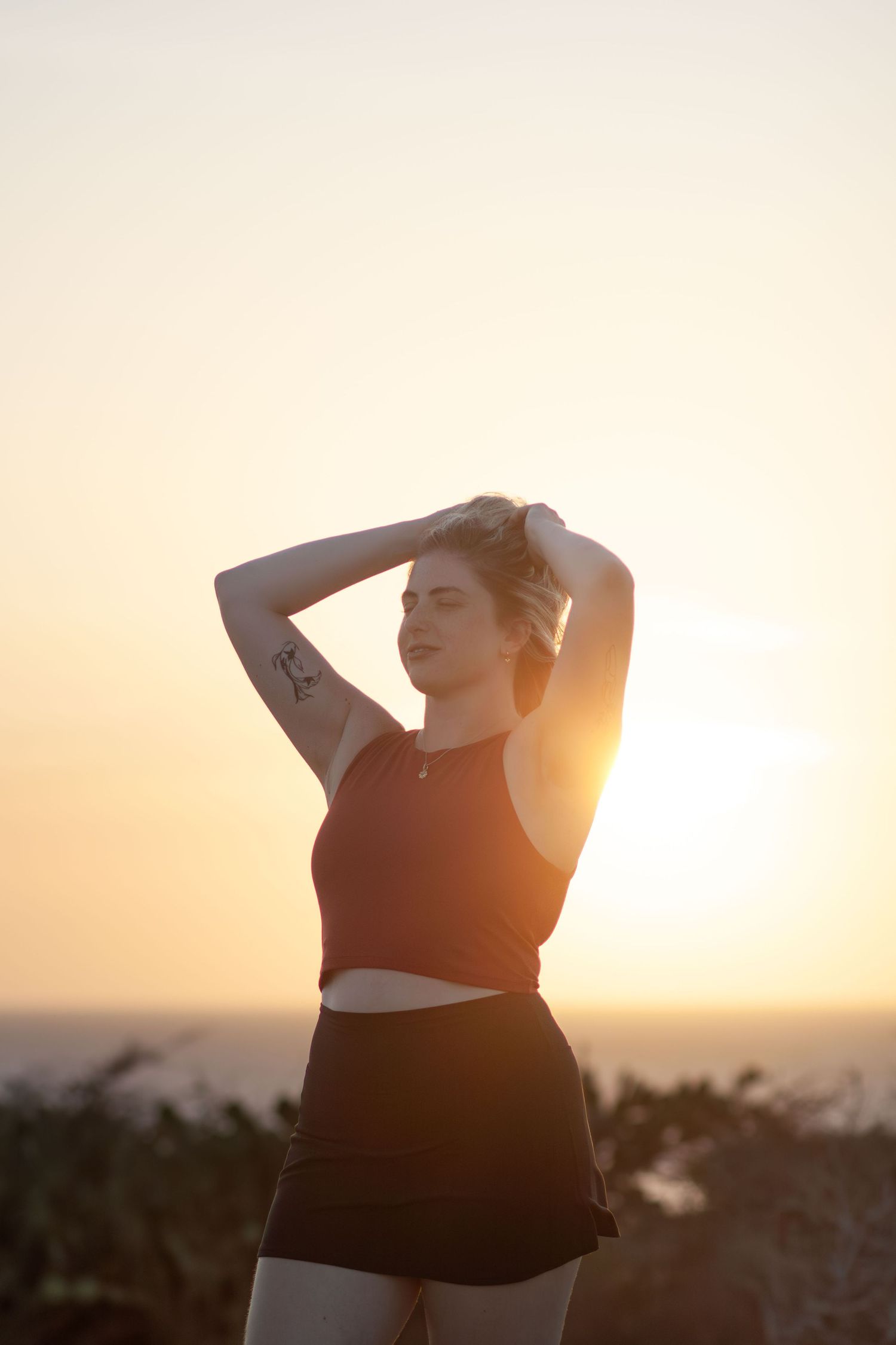 A silhouetted figure poses against a warm sunset sky creating a dramatic backlit effect.