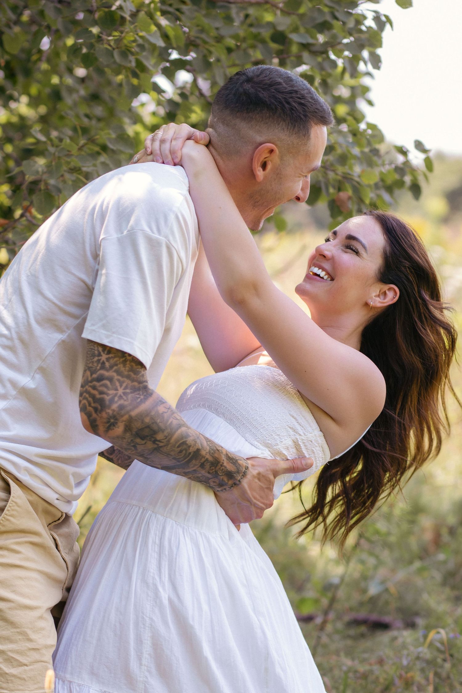 A couple shares a playful dip while embracing in a natural outdoor setting.