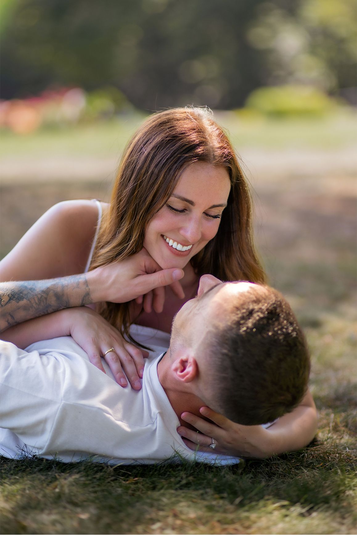 Couple lying in grass shares intimate moment during outdoor photoshoot.