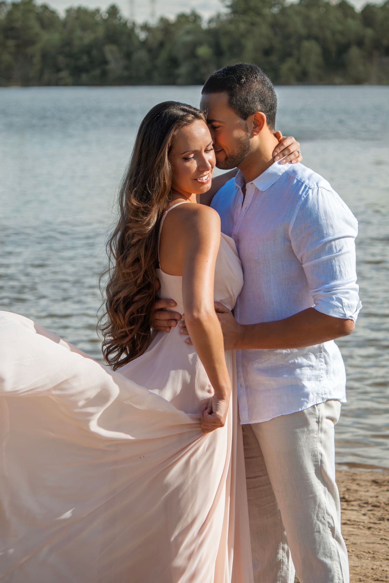 Romantic lakeside photoshoot with a couple in light summer clothing.