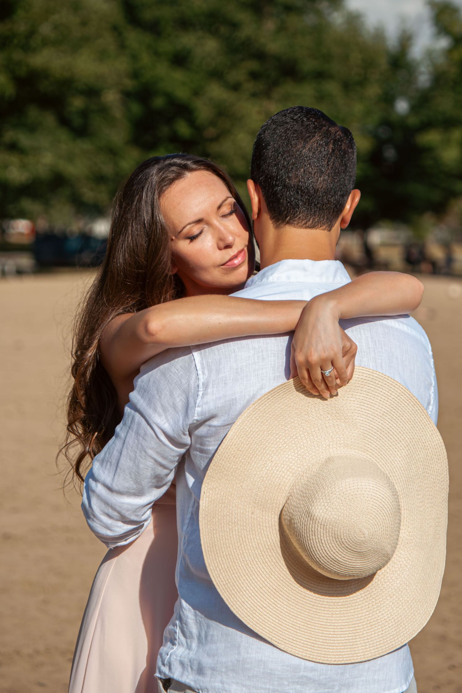 Close-up series of couple embracing on beach with straw hat and natural lighting.