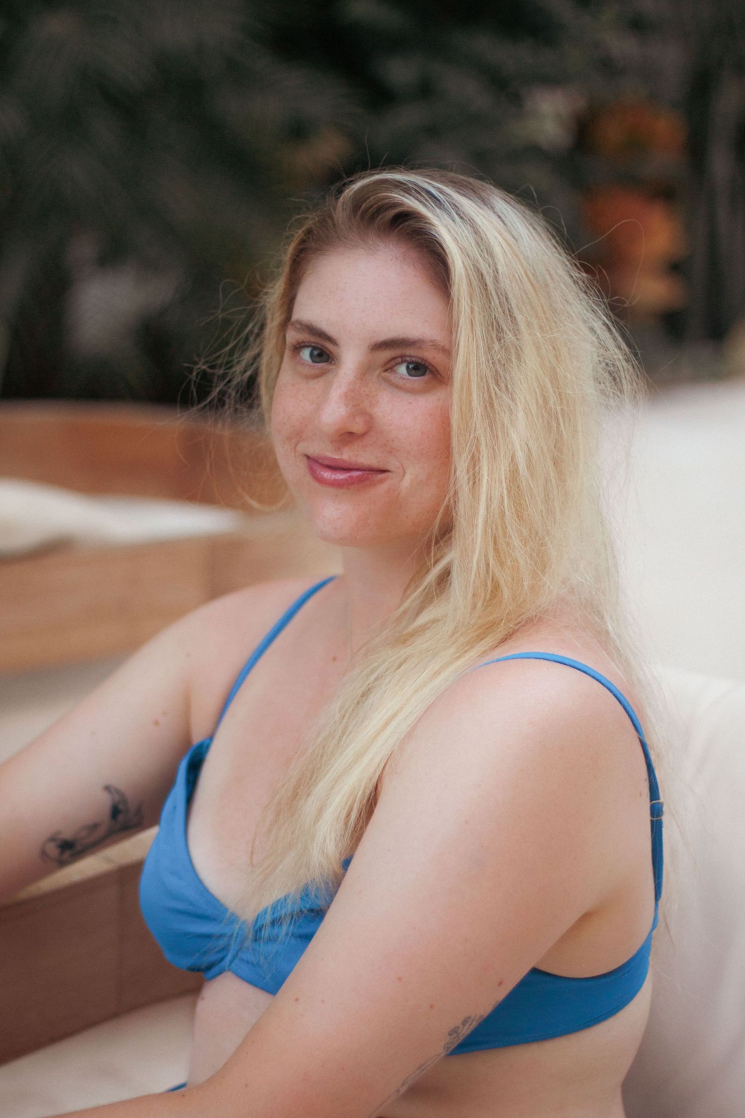 Woman with blonde hair posing in a bright blue swimsuit against a blurred background.
