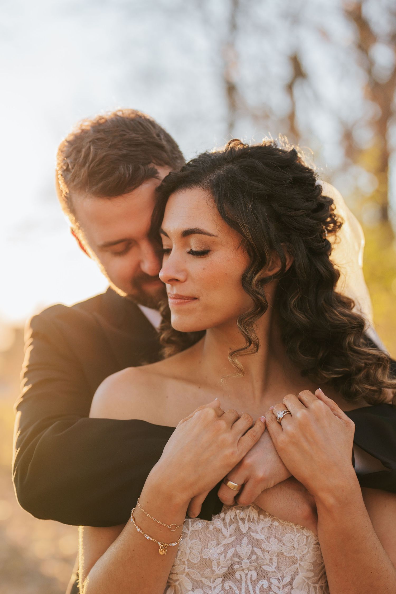 A romantic golden hour wedding portrait shows a tender embrace between the couple with light flares in the background.  Central Indiana