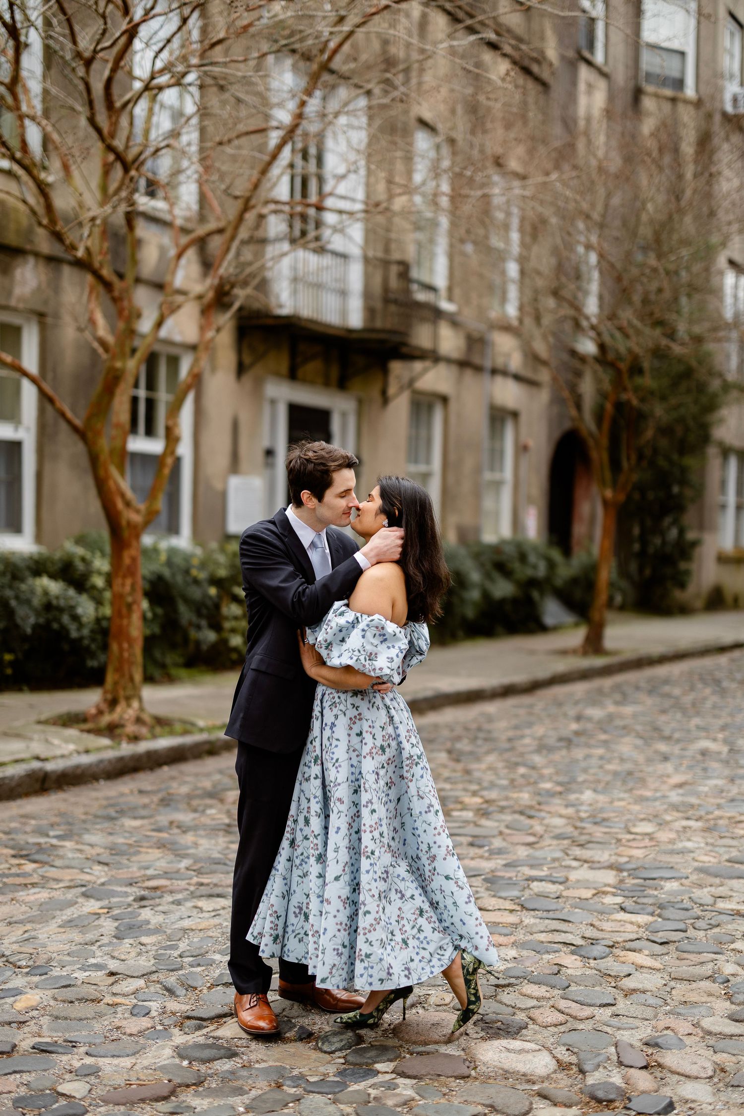A romantic moment on a cobblestone street between a couple in formal attire.