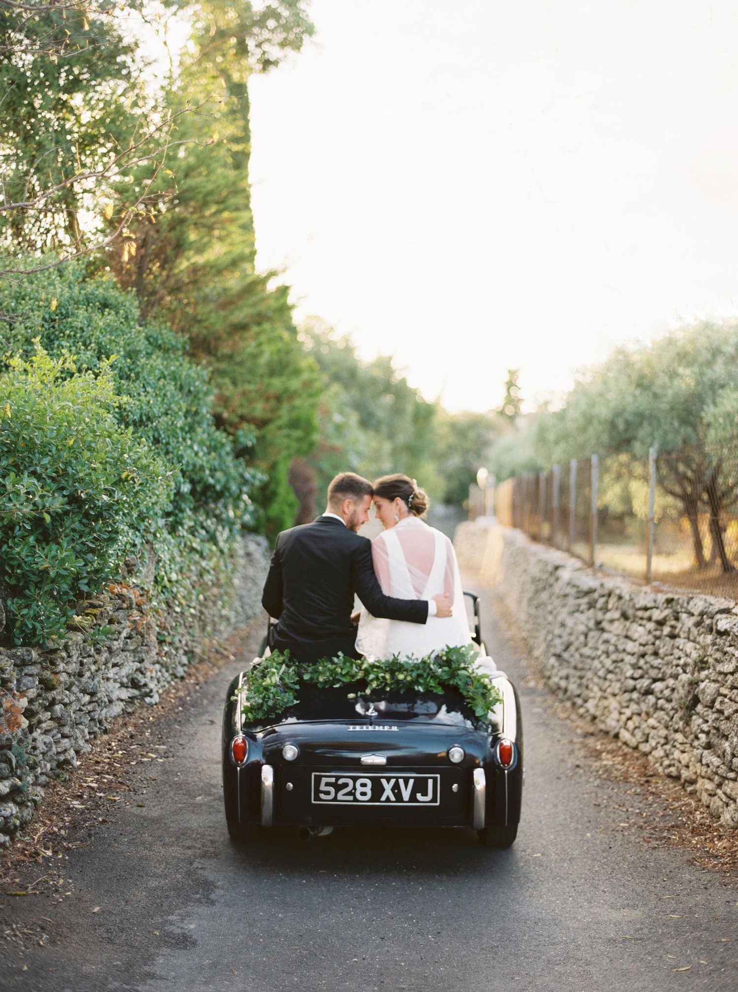 Romantic wedding couple in a vintage car at La Bastide, Gordes, Provence, France, surrounded by scenic countryside.