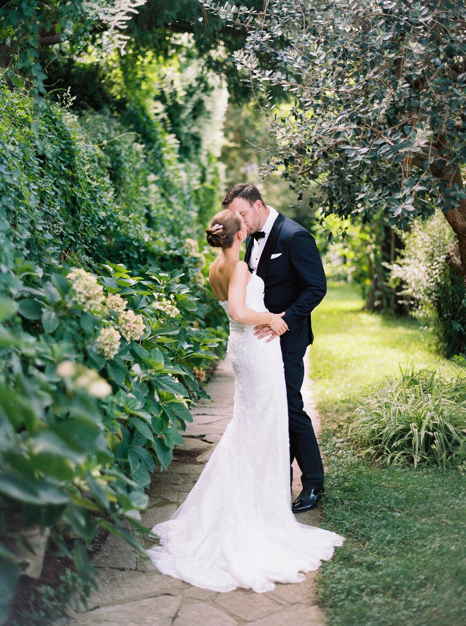 Romantic wedding couple kissing in lush gardens of Villa San Michele, Capri, Italy, capturing timeless elegance.