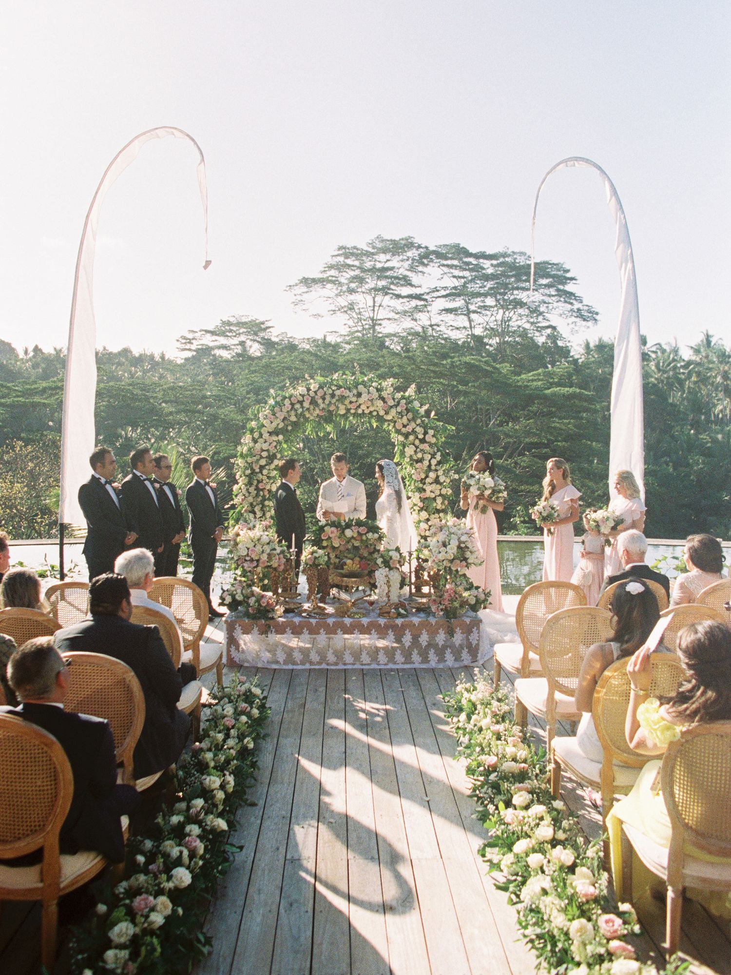 Romantic wedding ceremony at Four Seasons Ubud, Bali, with lush greenery, elegant floral decor.