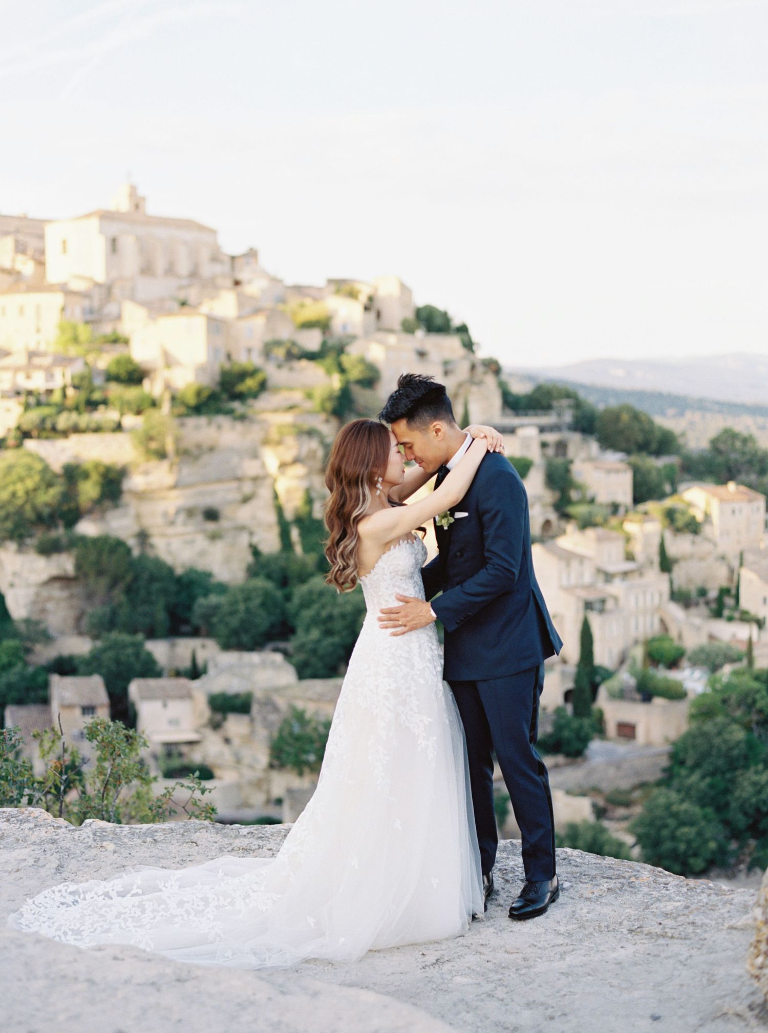 Romantic wedding portrait at La Bastide, Gordes, Provence, France, with a couple embracing and scenic village views.