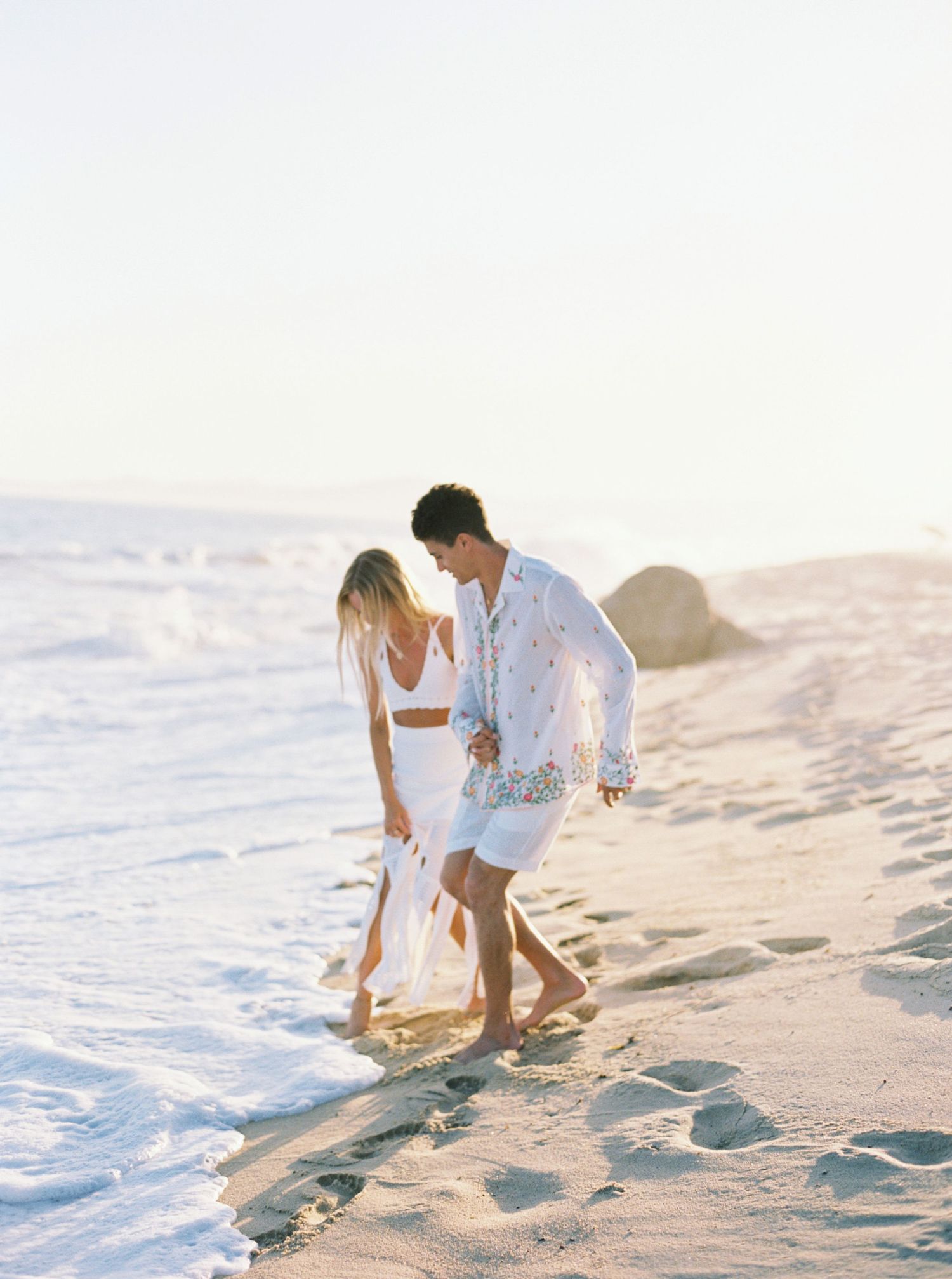Bride and groom posing on Los Cabos beach, captured by renowned wedding photographer in Mexico.