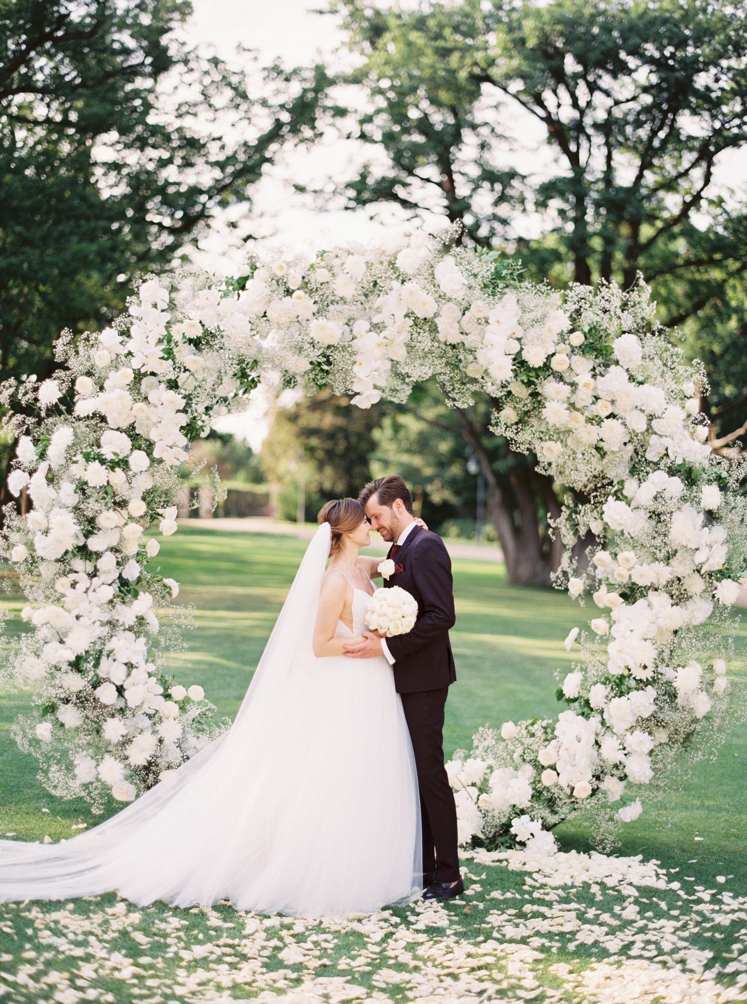 Elegant wedding portrait at Château Mcely, Czech Republic, with a romantic floral arch and timeless outdoor celebration.