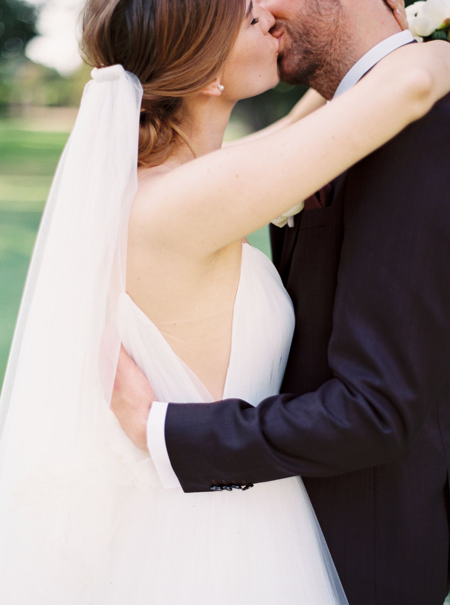 Newlyweds embrace in a romantic kiss at the park, photographed by a top wedding photographer at Chateau Mcely.
