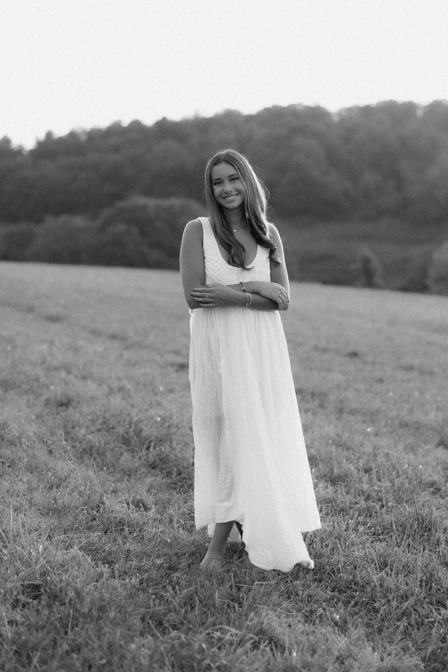 A black and white photo series shows someone in a flowing white dress standing in a grassy meadow at dusk.