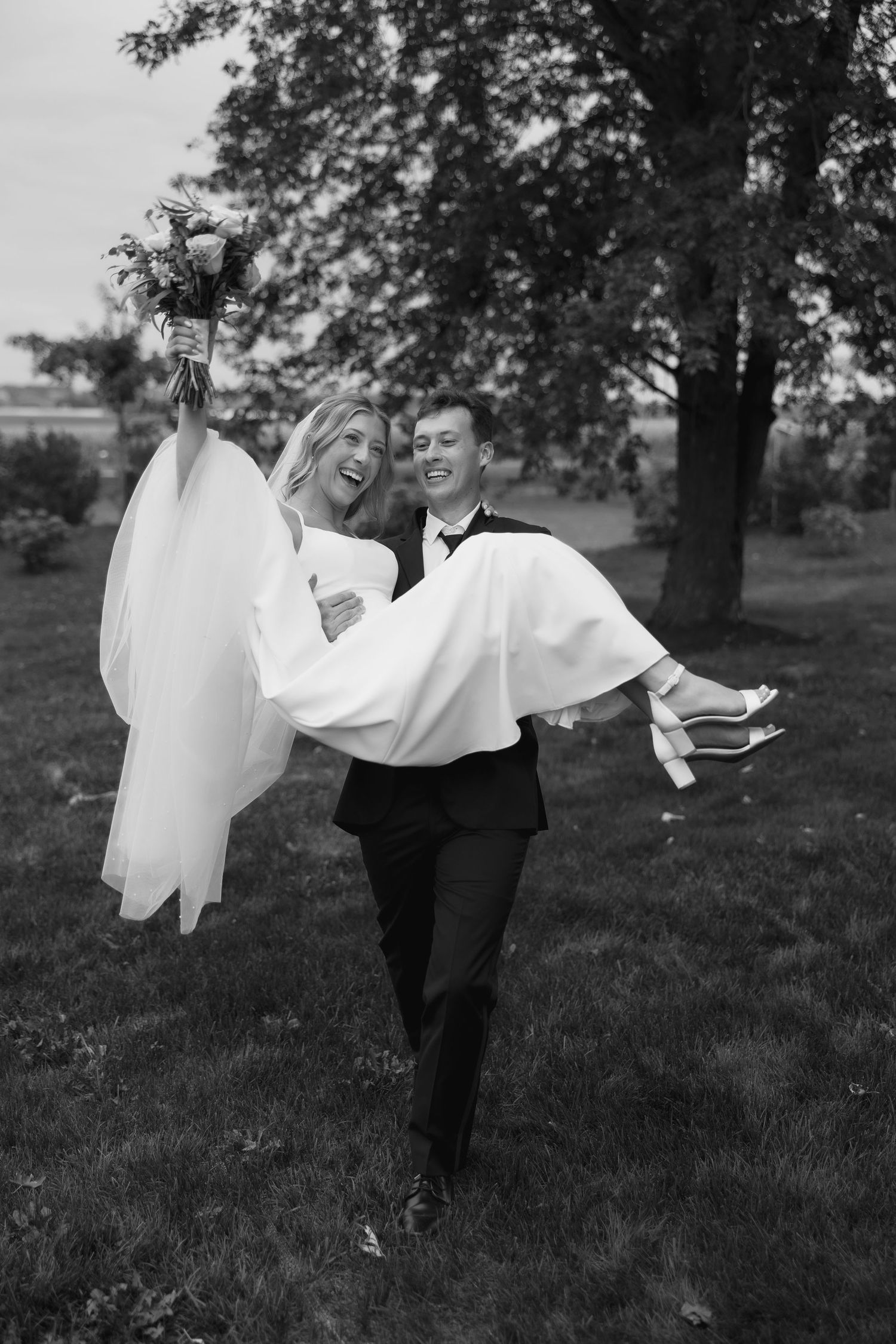 Playful black and white photo of couple spinning in an open field.