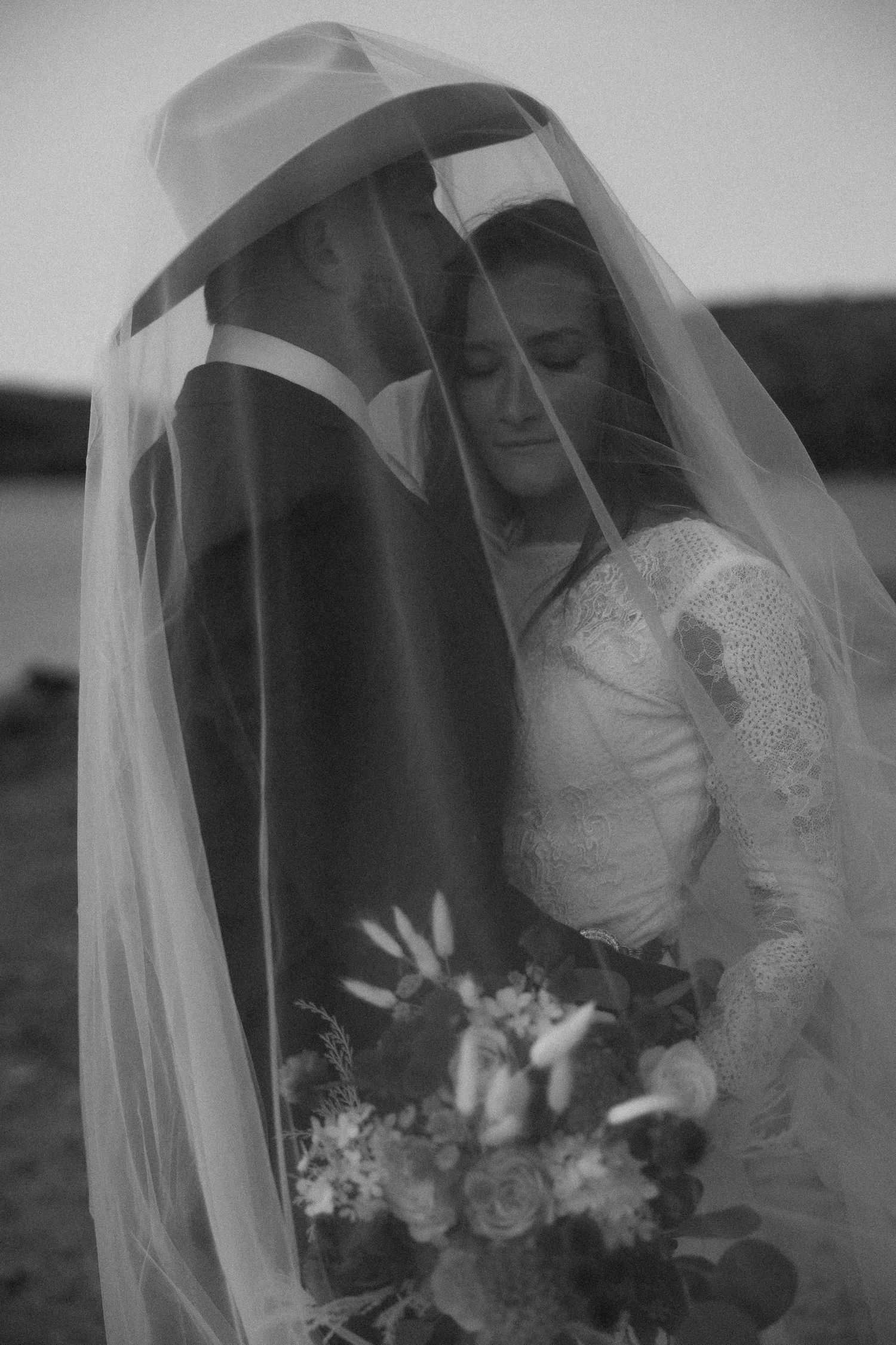 Black and white bridal portrait series showing a veiled bride with bouquet in romantic poses.