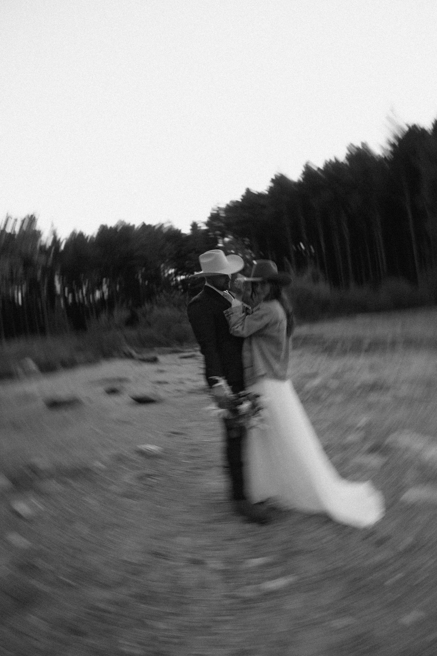 Blurred black and white action shot of movement in an outdoor field with trees.