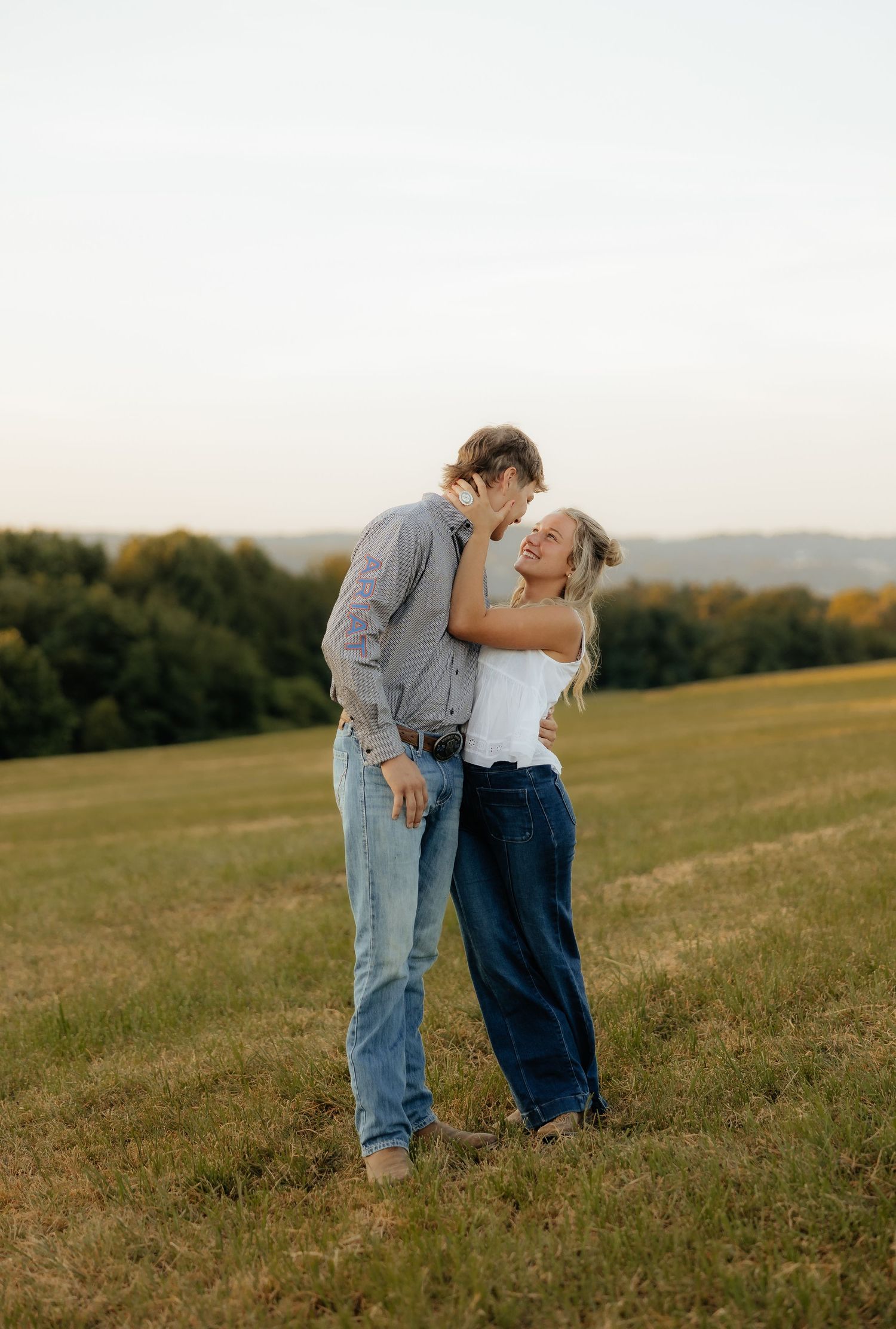 A couple shares a tender moment together in a golden field during sunset.