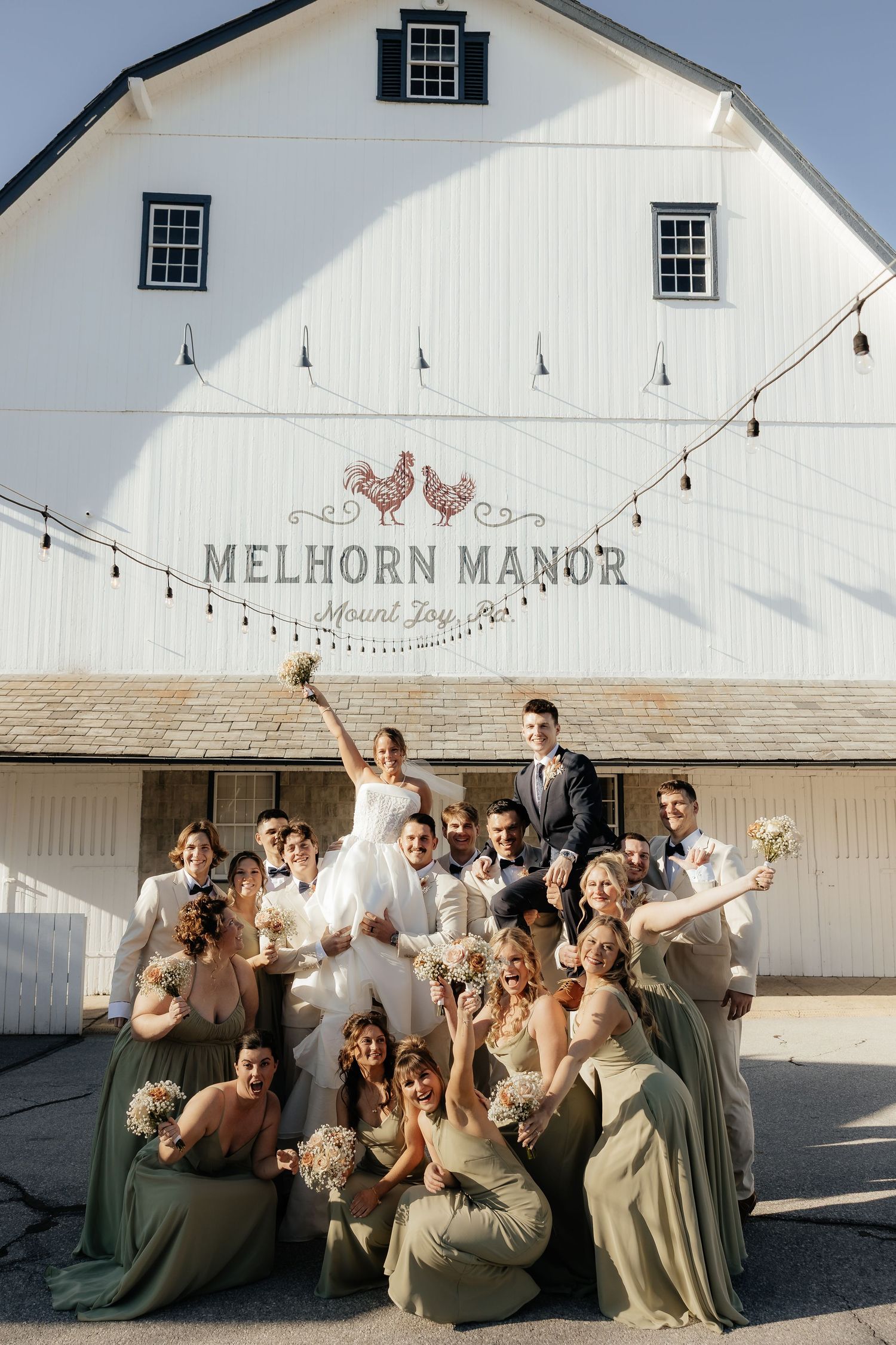 Wedding party celebrating in front of Melhorn Manor barn in Mount Joy, bridesmaids in sage green gowns.