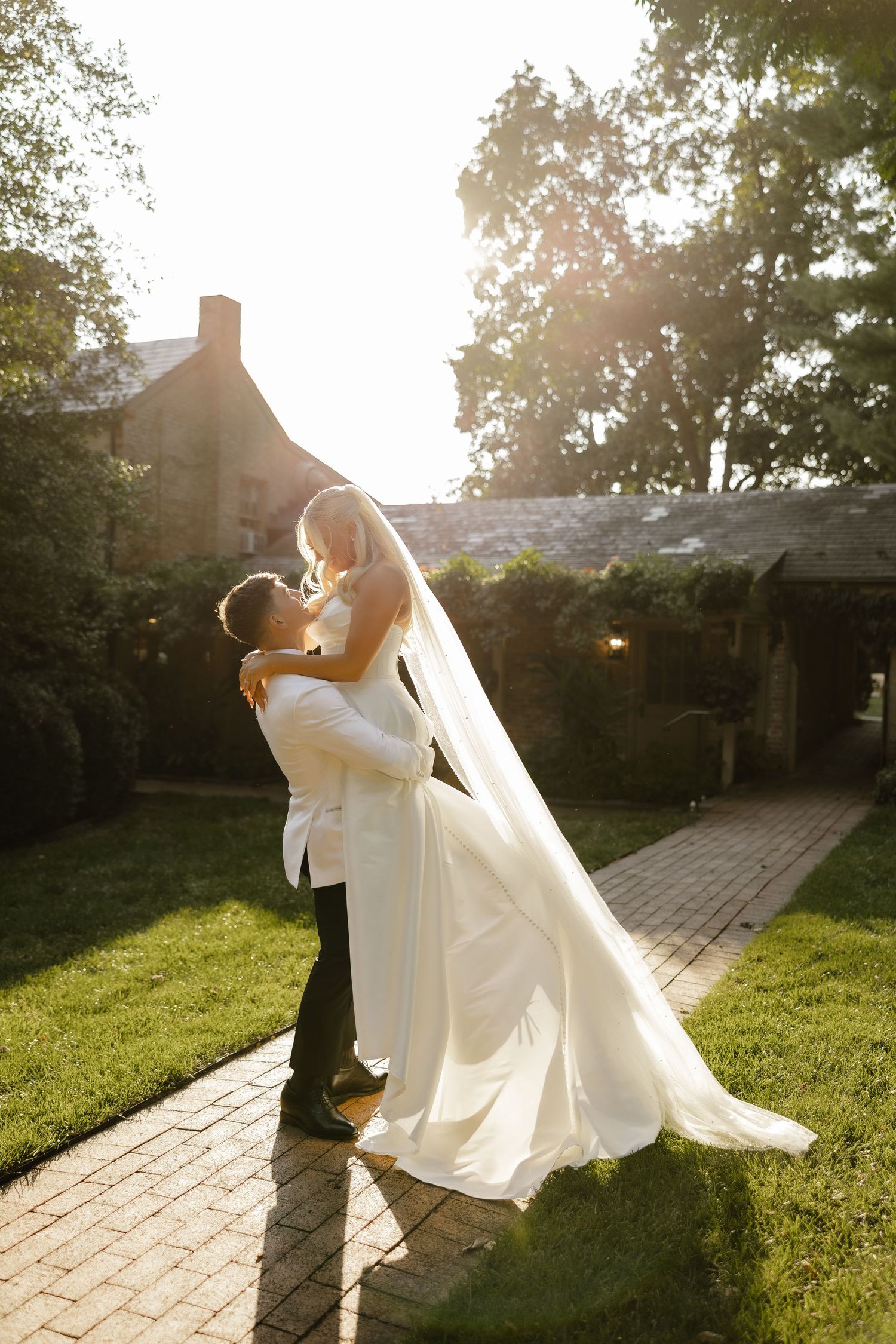 Romantic sunset wedding photos with couple dancing on stone pathway.