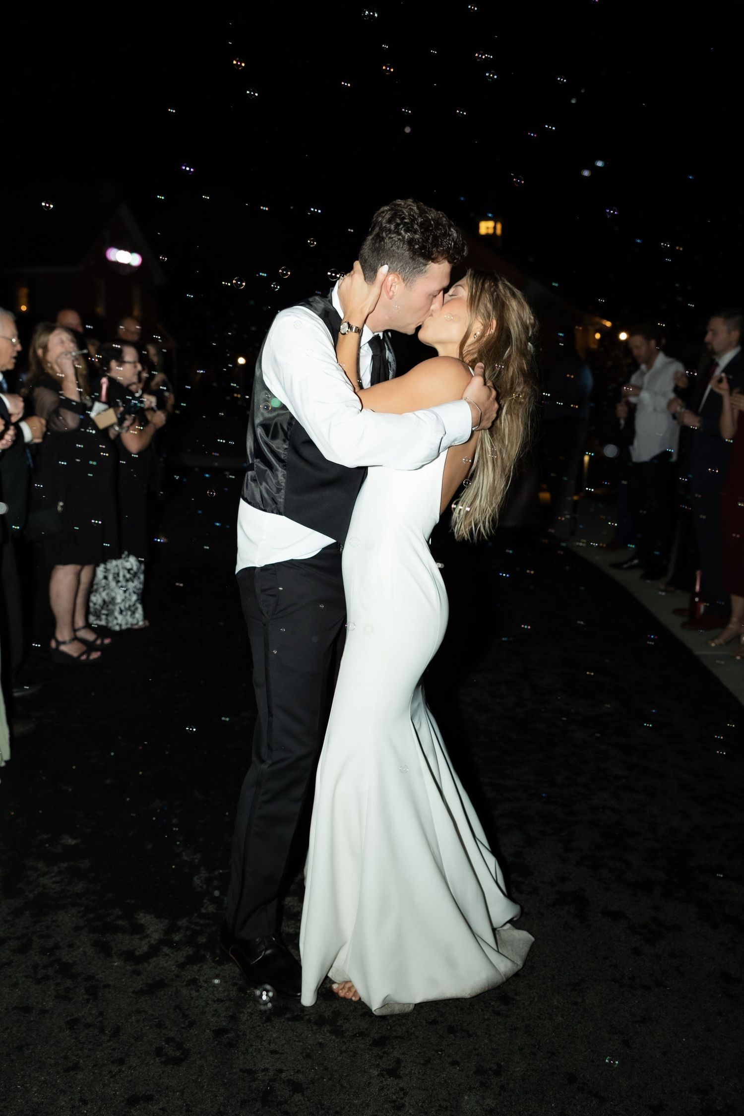 Wedding dance celebration at night with confetti falling in dark reception venue.