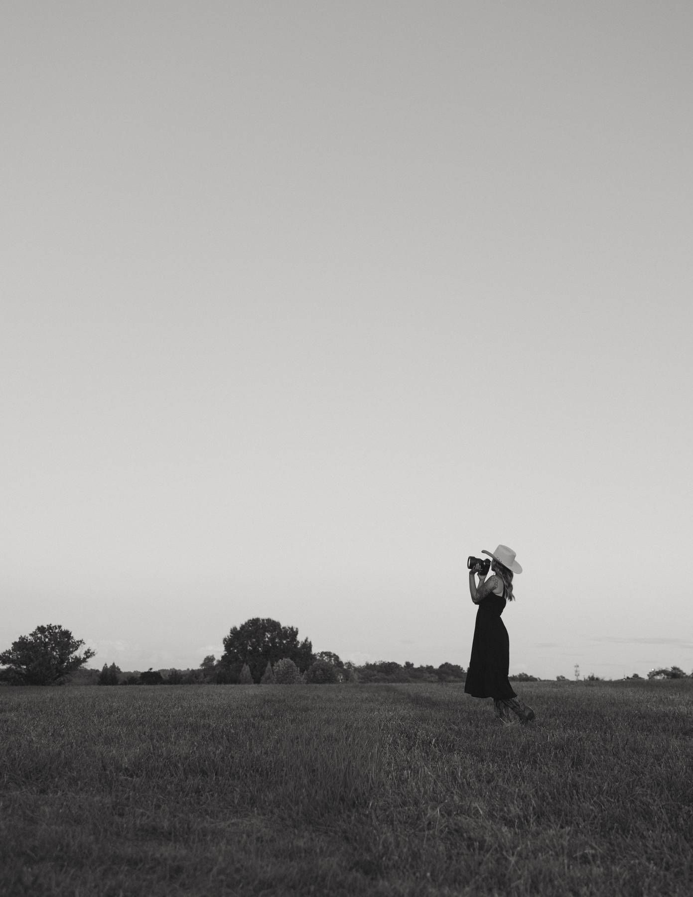Silhouettes of photographers capturing shots in an open field at dusk.