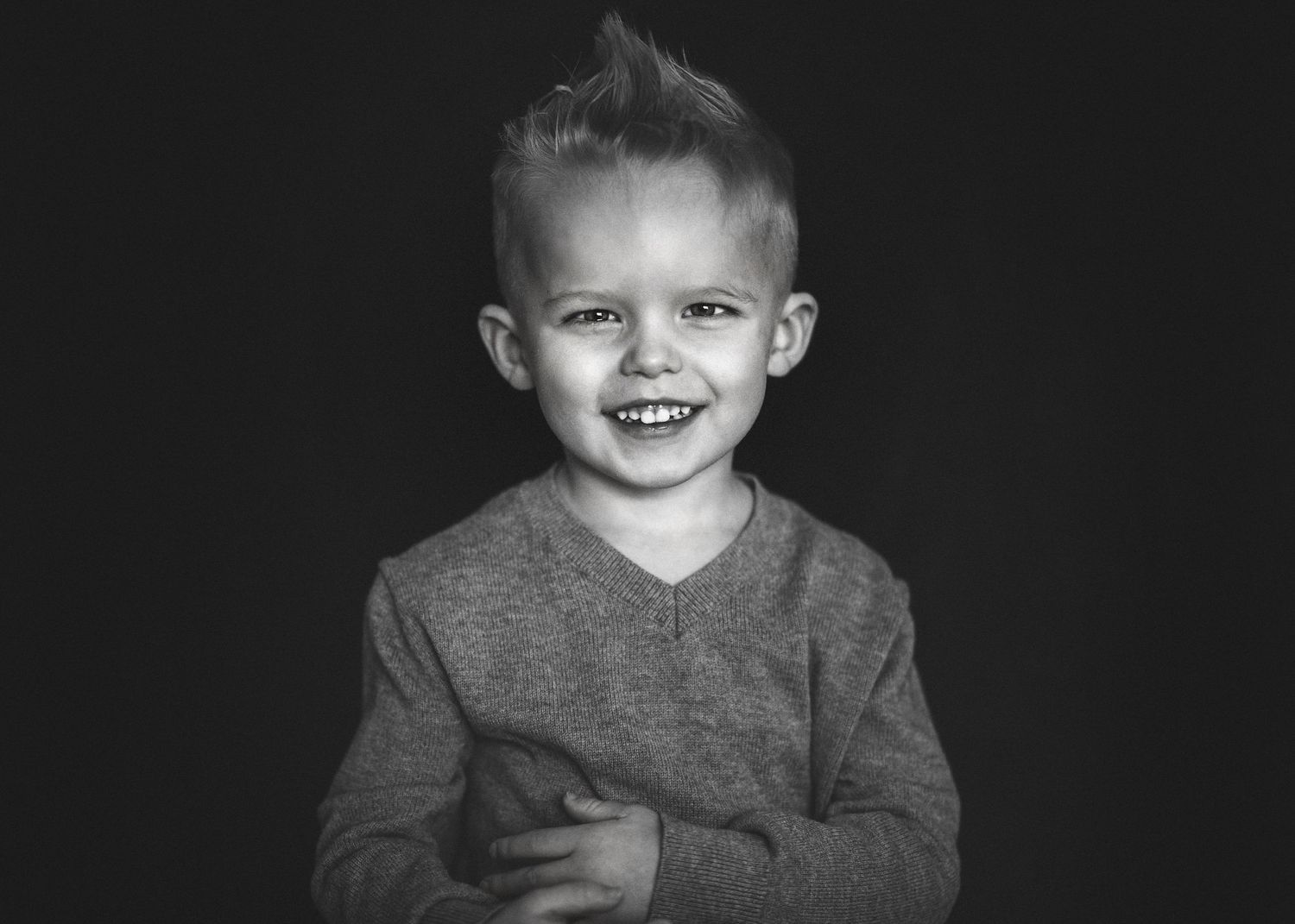 Black and white image of little boy smiling in studio