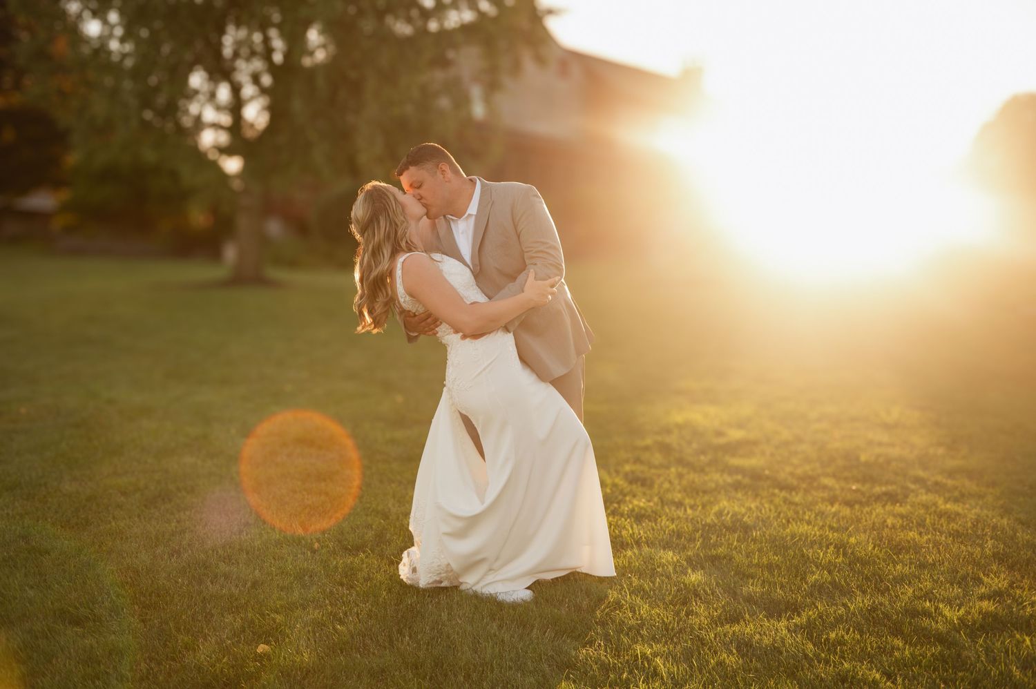 A romantic moment captured in golden sunlight on a grassy lawn with lens flare during sunset.