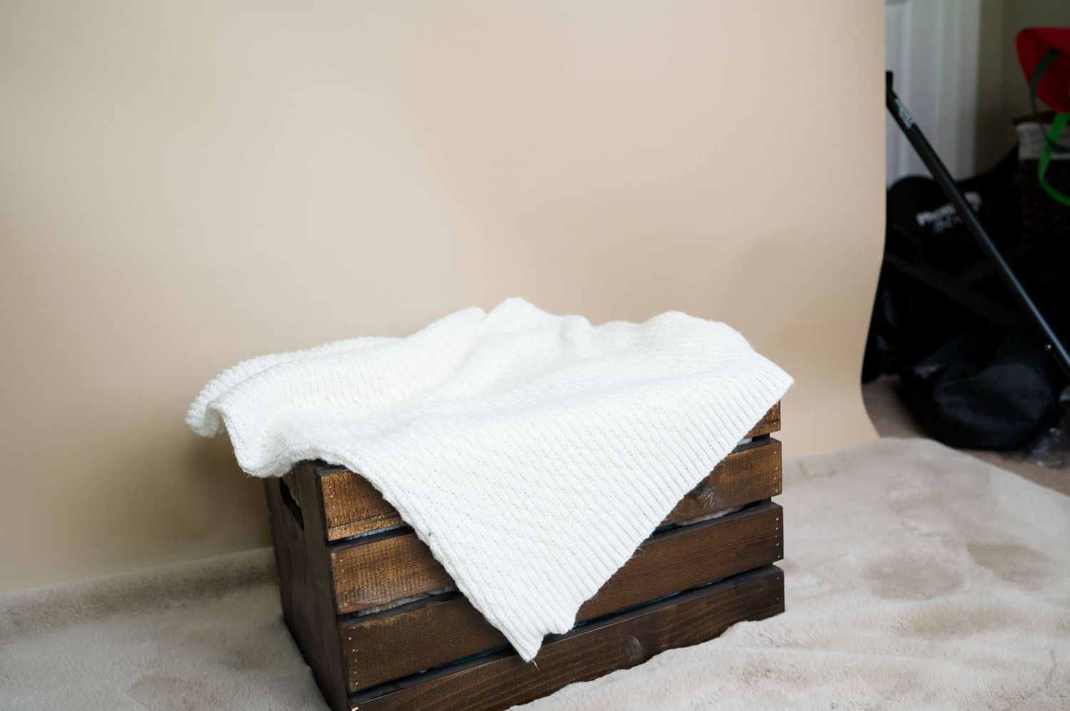 White textiles are arranged on wooden crates against a beige wall, creating a minimalist display setup.