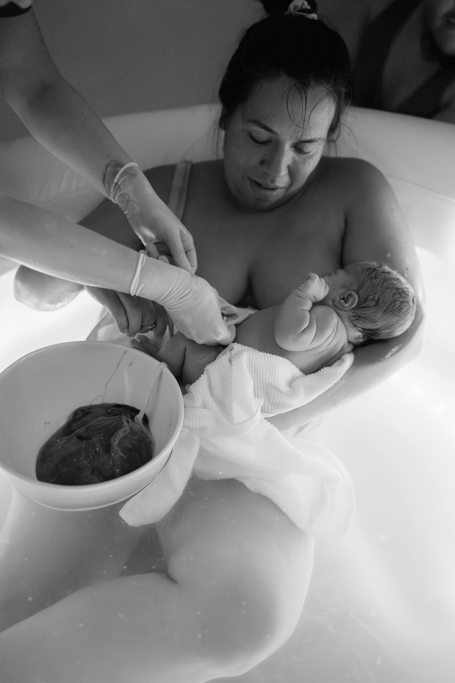 mother cutting the umbilical cord after baby's delivery at home in Frederick, MD