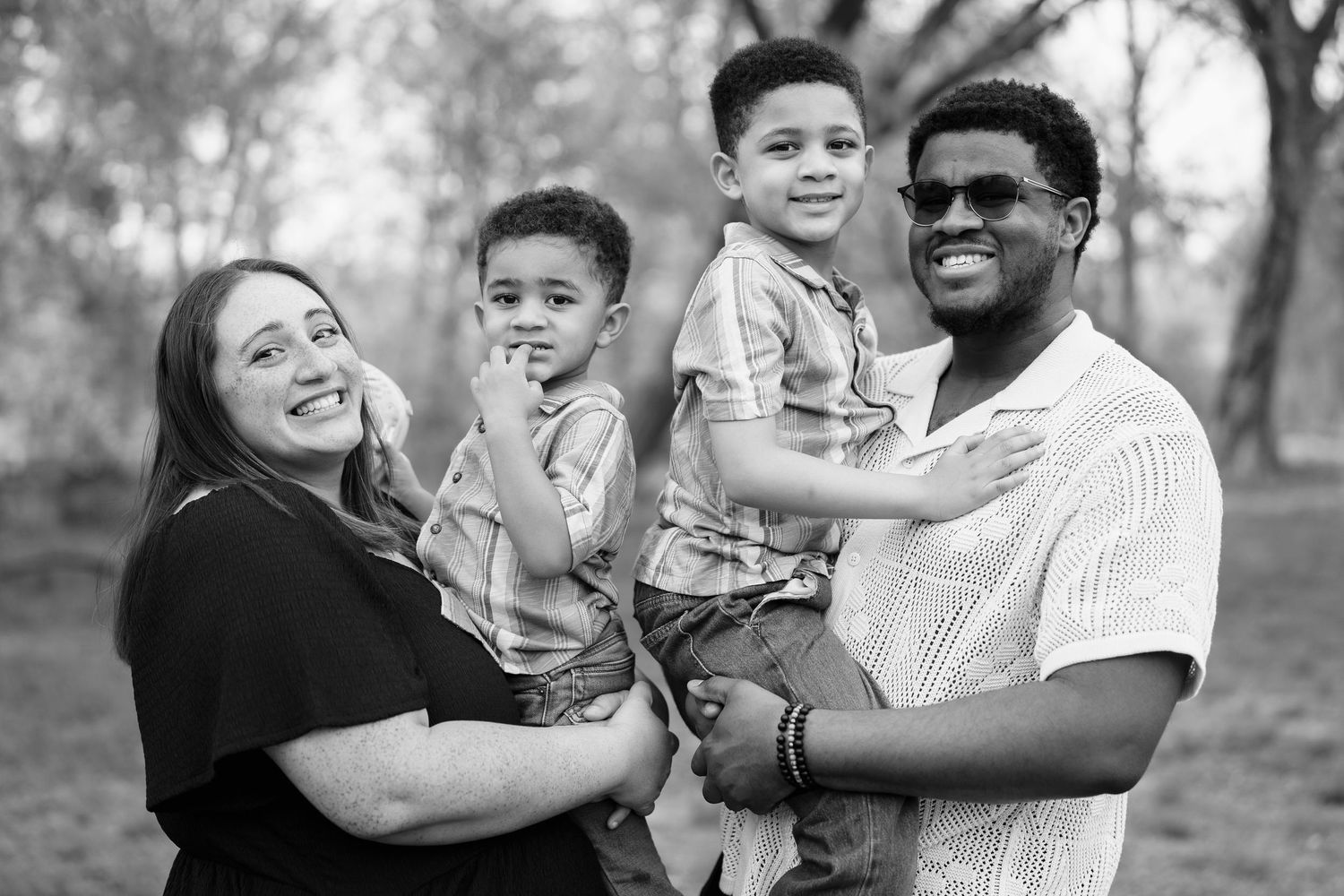 A black and white photo series showing a happy family embracing and laughing together outdoors in a natural setting, in Arlington, VA