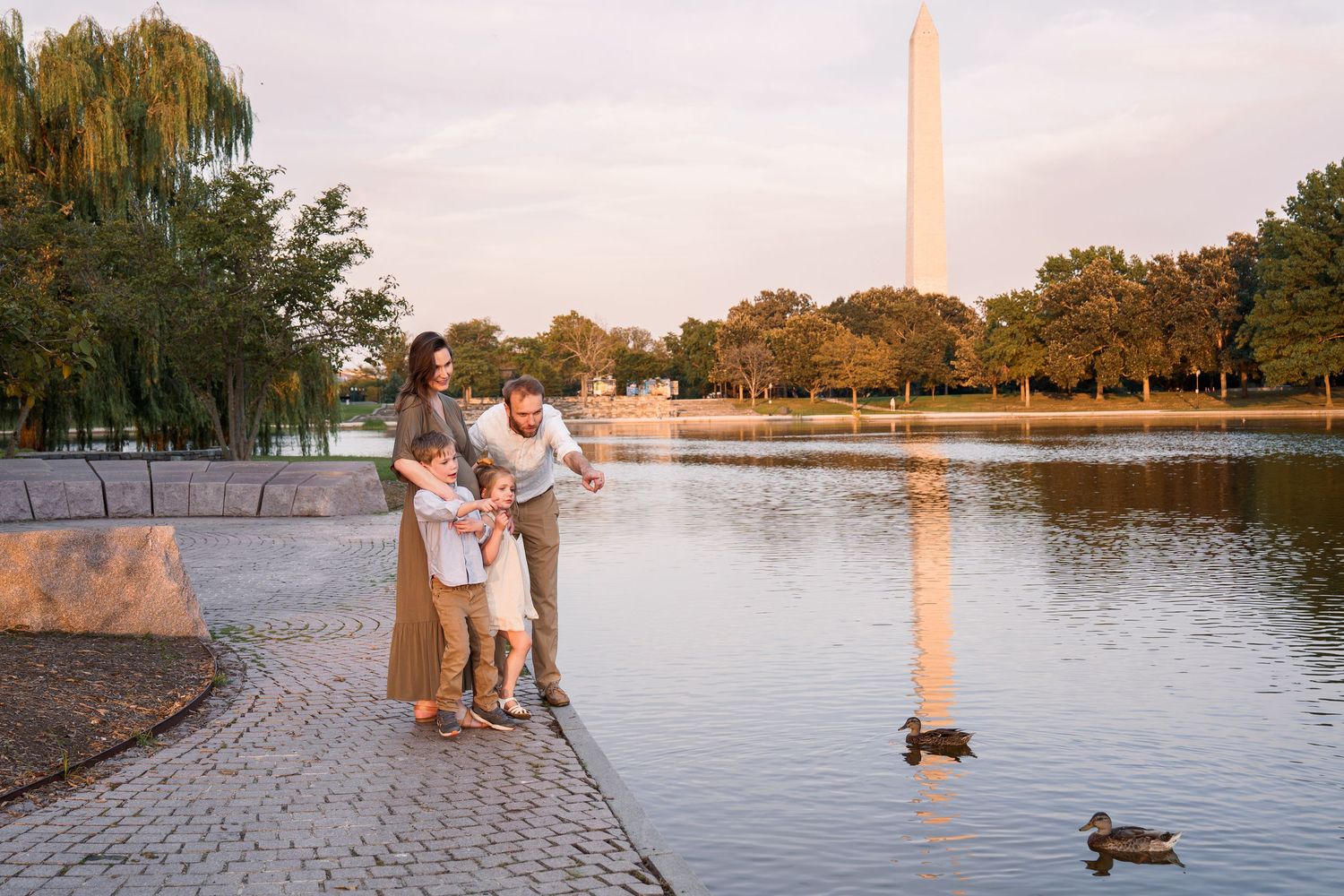 Family posing by the Reflecting Pool with the Washington Monument in the background at sunset in Washington DC.