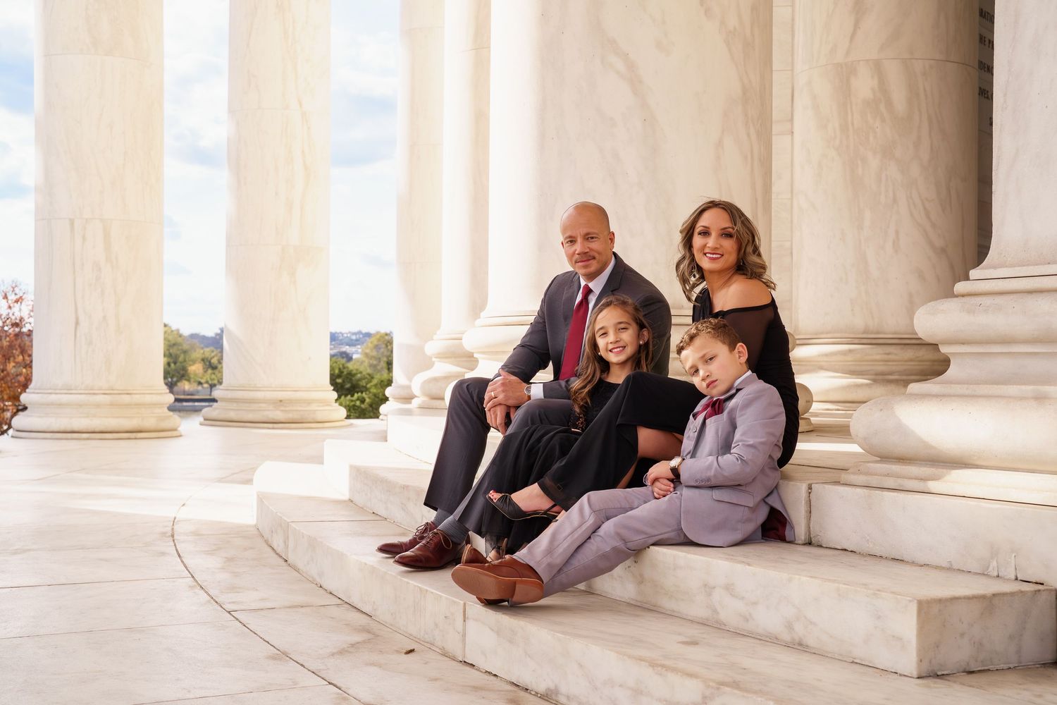 Family of four posing on marble steps between grand columns at a historic monument at the Jefferson Memorial in Washington DC