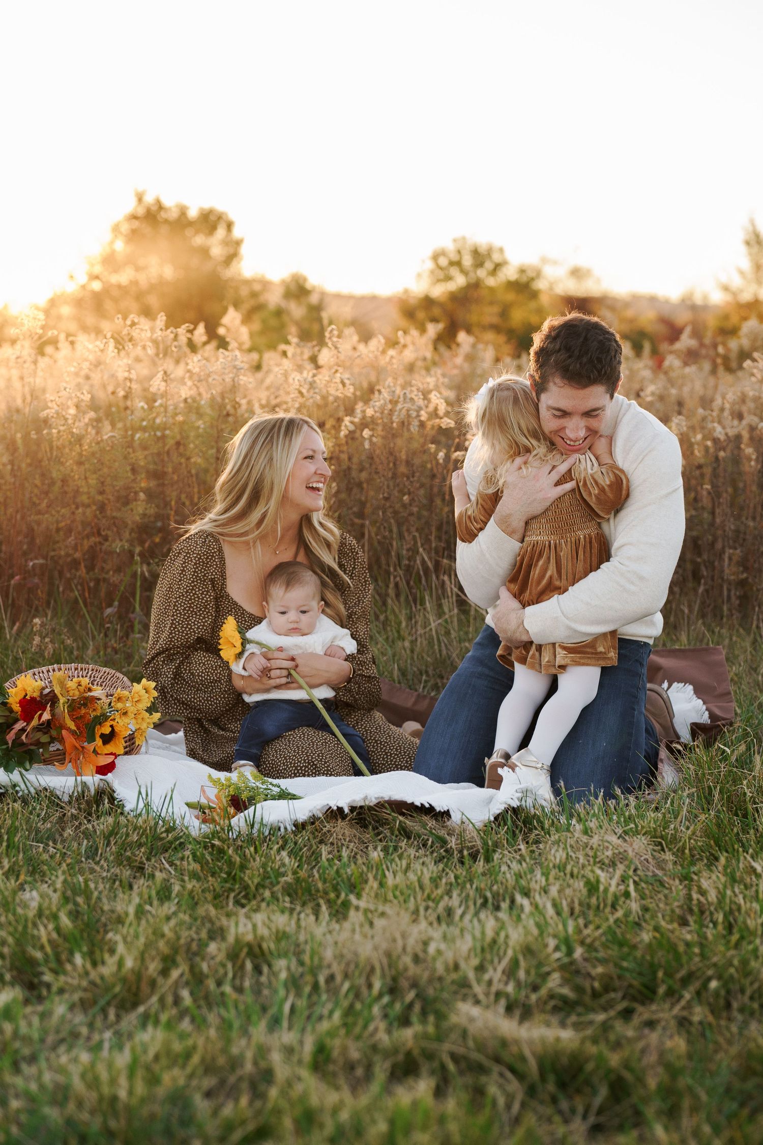 Family of four laughing together in the golden light at Baker Park, Frederick MD.