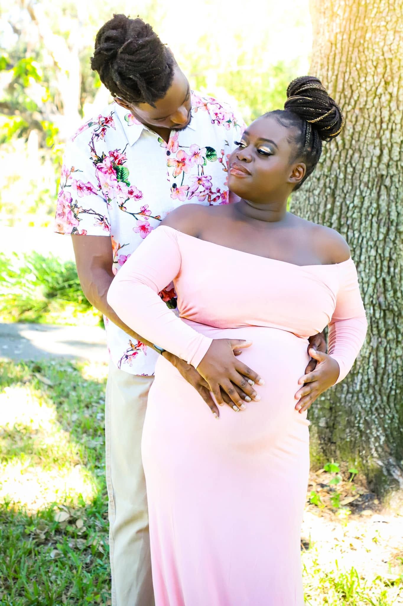Maternity portrait of a couple sharing a tender moment outdoors, with the man embracing a pregnant woman in Winter Garden, Florida.
