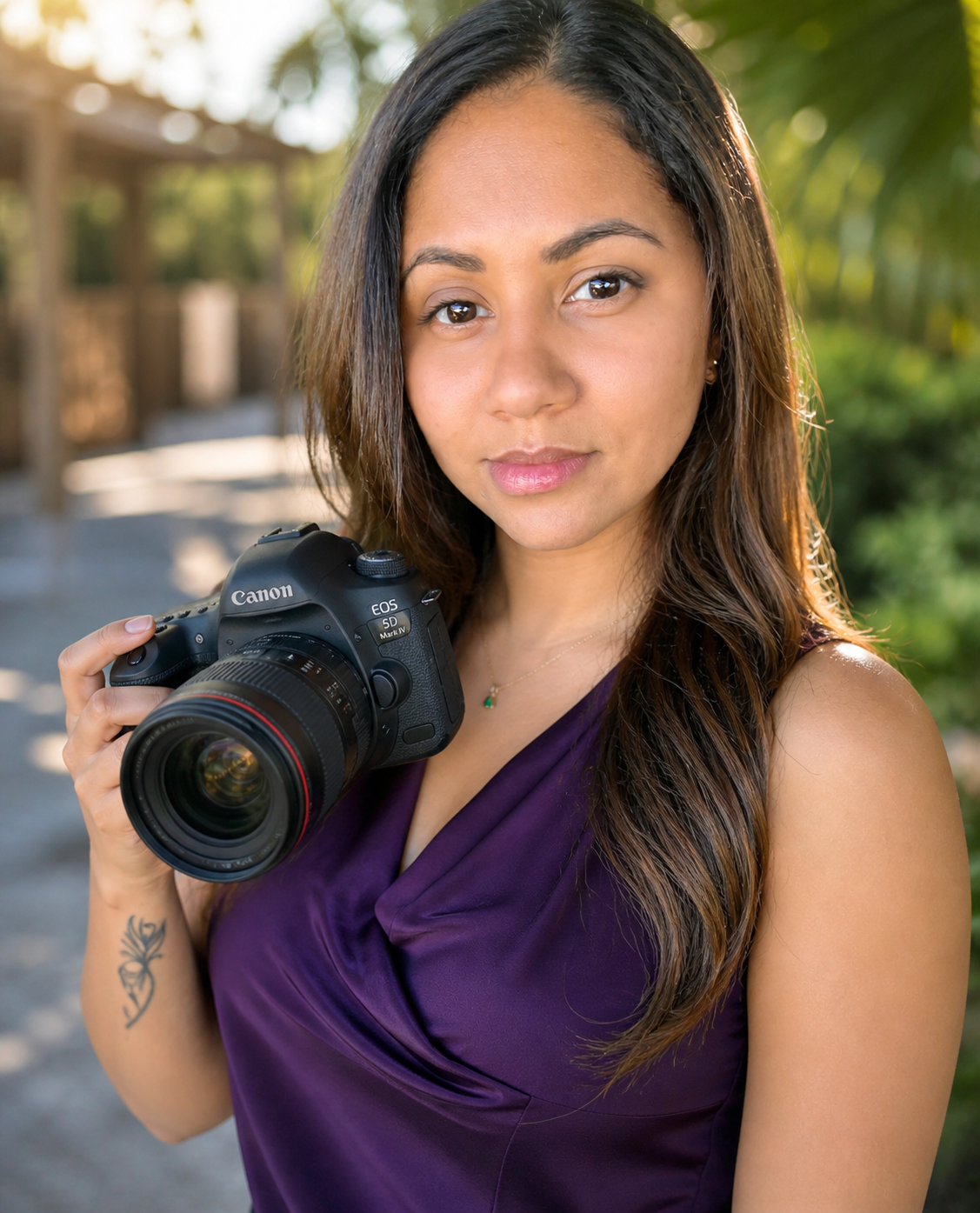 Professional female photographer holding Canon DSLR camera, wearing purple dress outdoors.