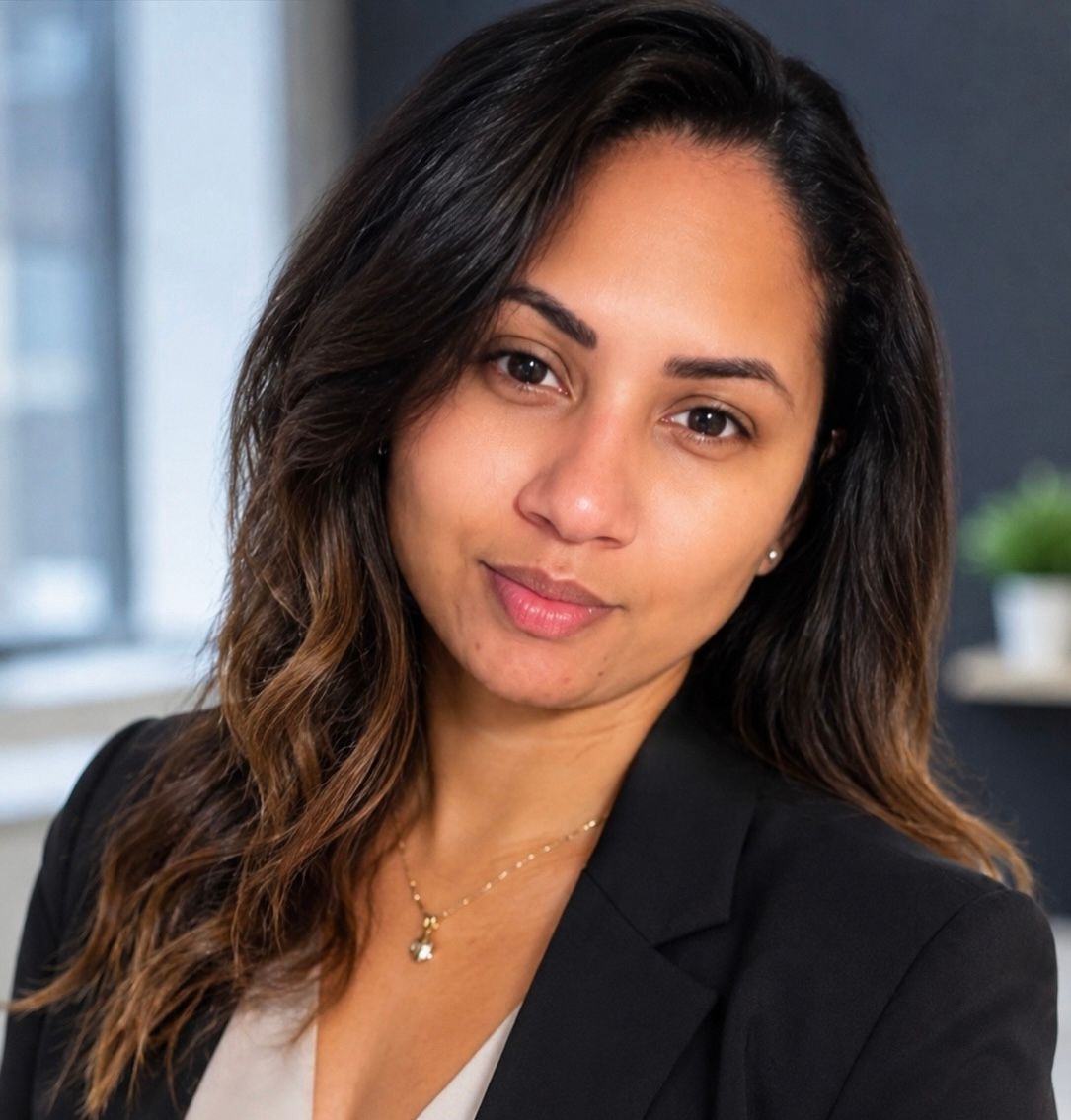Professional woman in black blazer posing for a corporate headshot in an office setting.